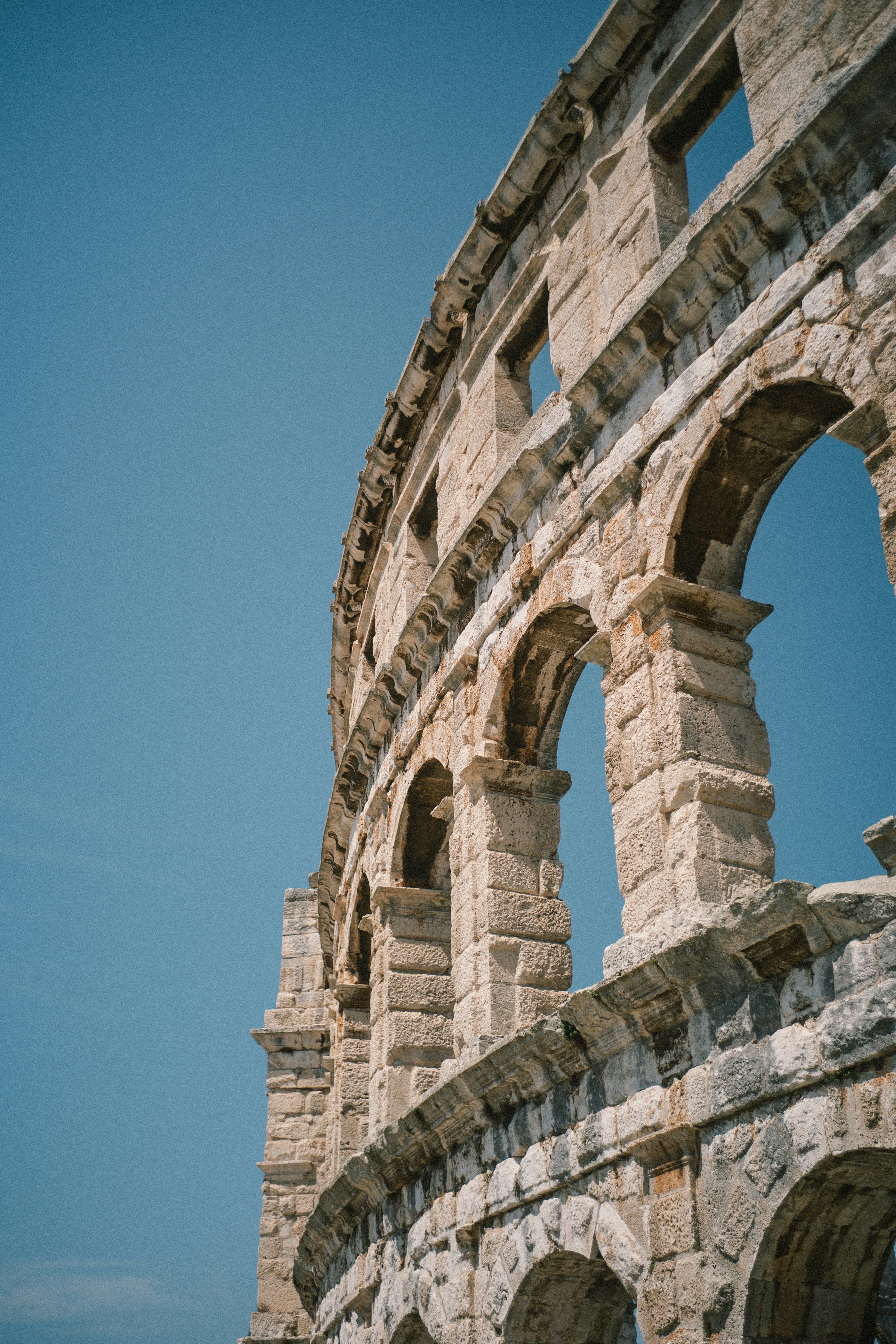 Ancient roman amphitheater arches against a clear blue sky