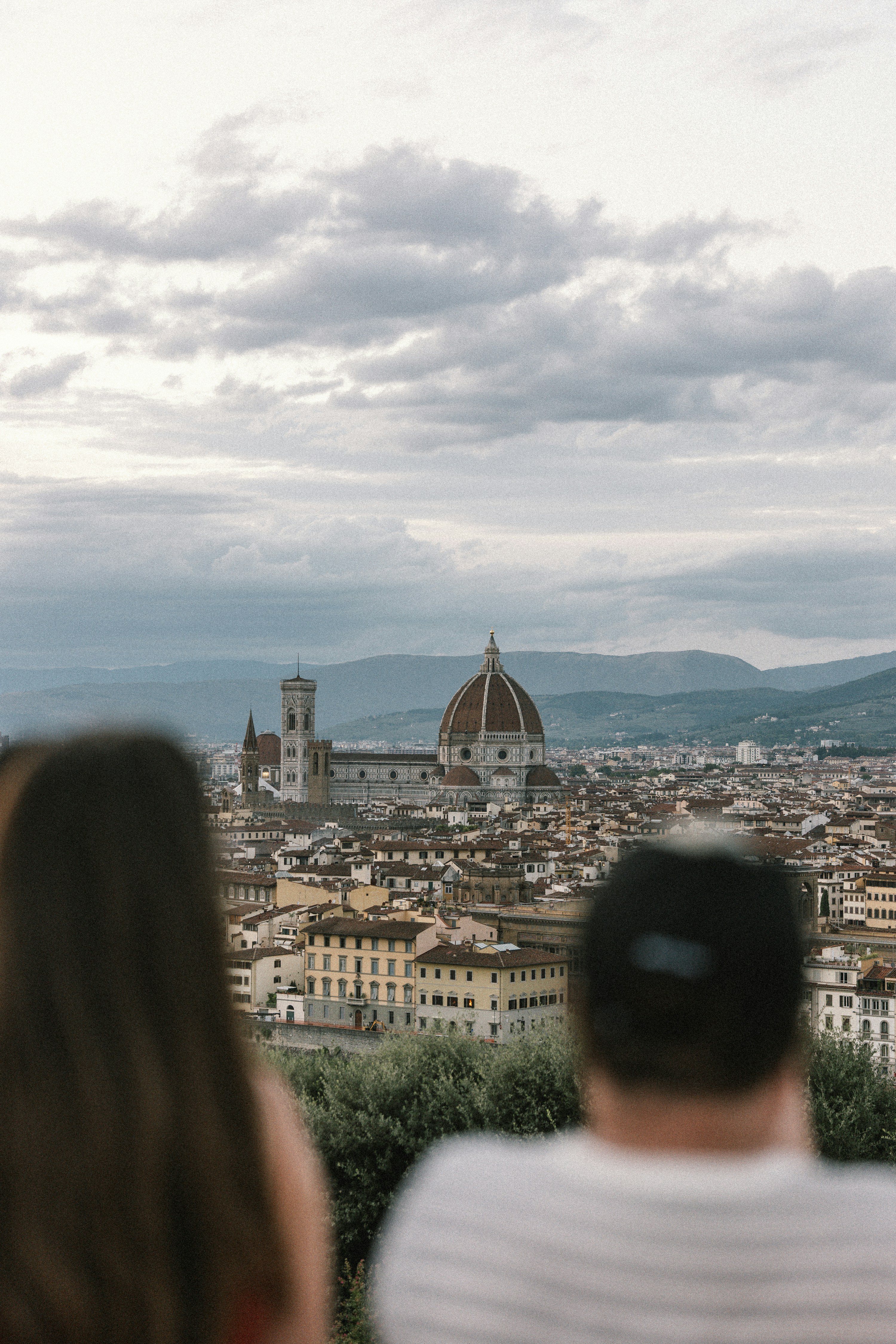 Two people observe the florence cityscape with its iconic dome