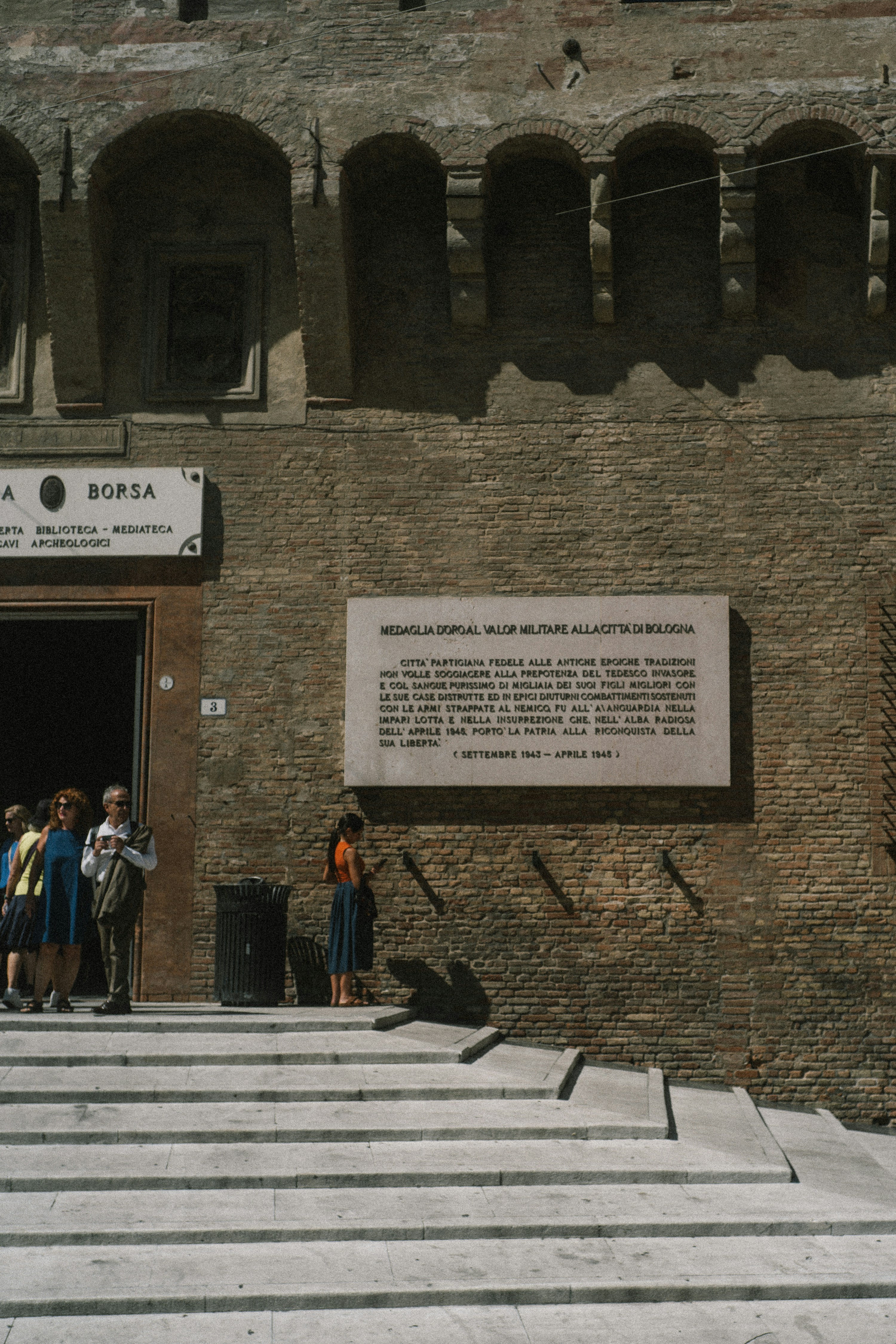 Historic brick building entrance with people and a commemorative plaque