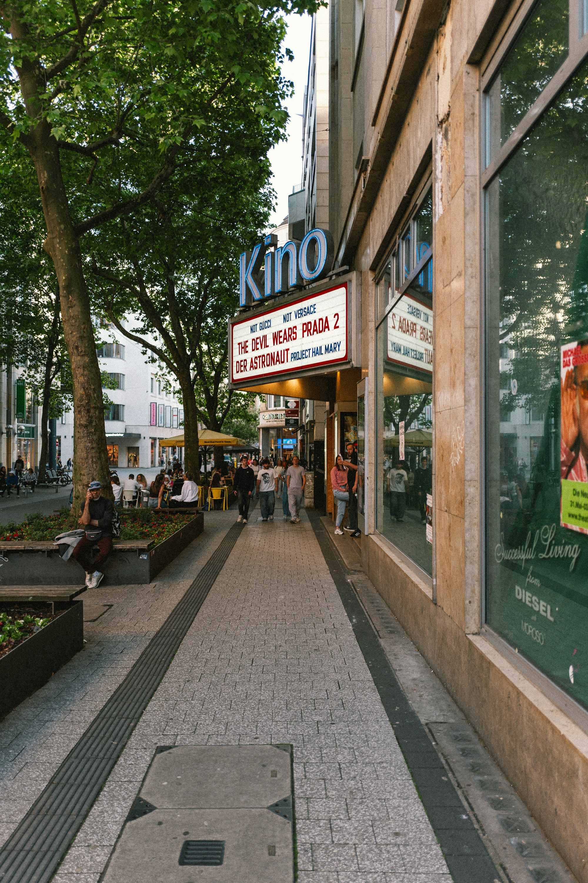 Cinema marquee illuminates a bustling city street with pedestrians