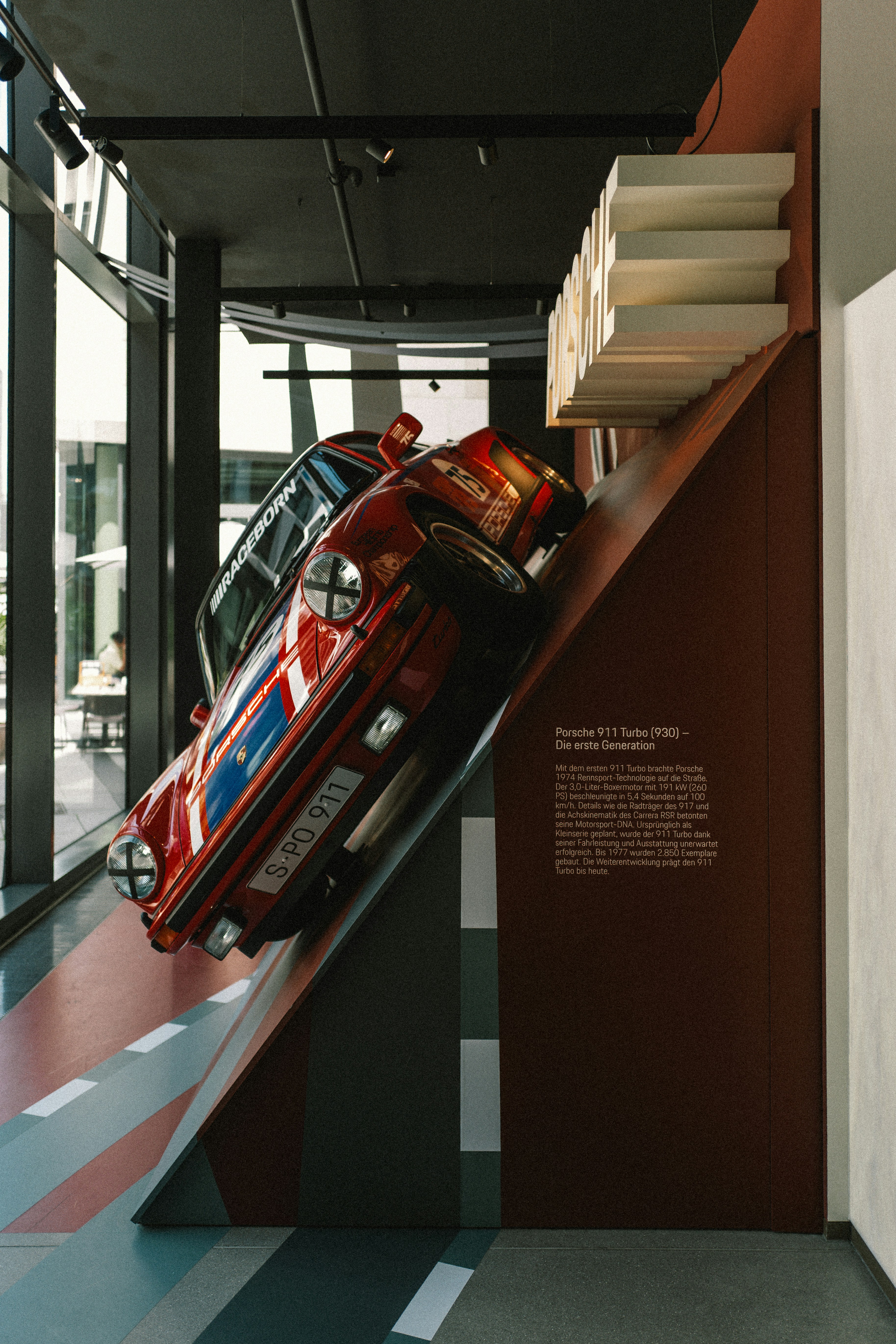 Red porsche car displayed on an inclined ramp indoors