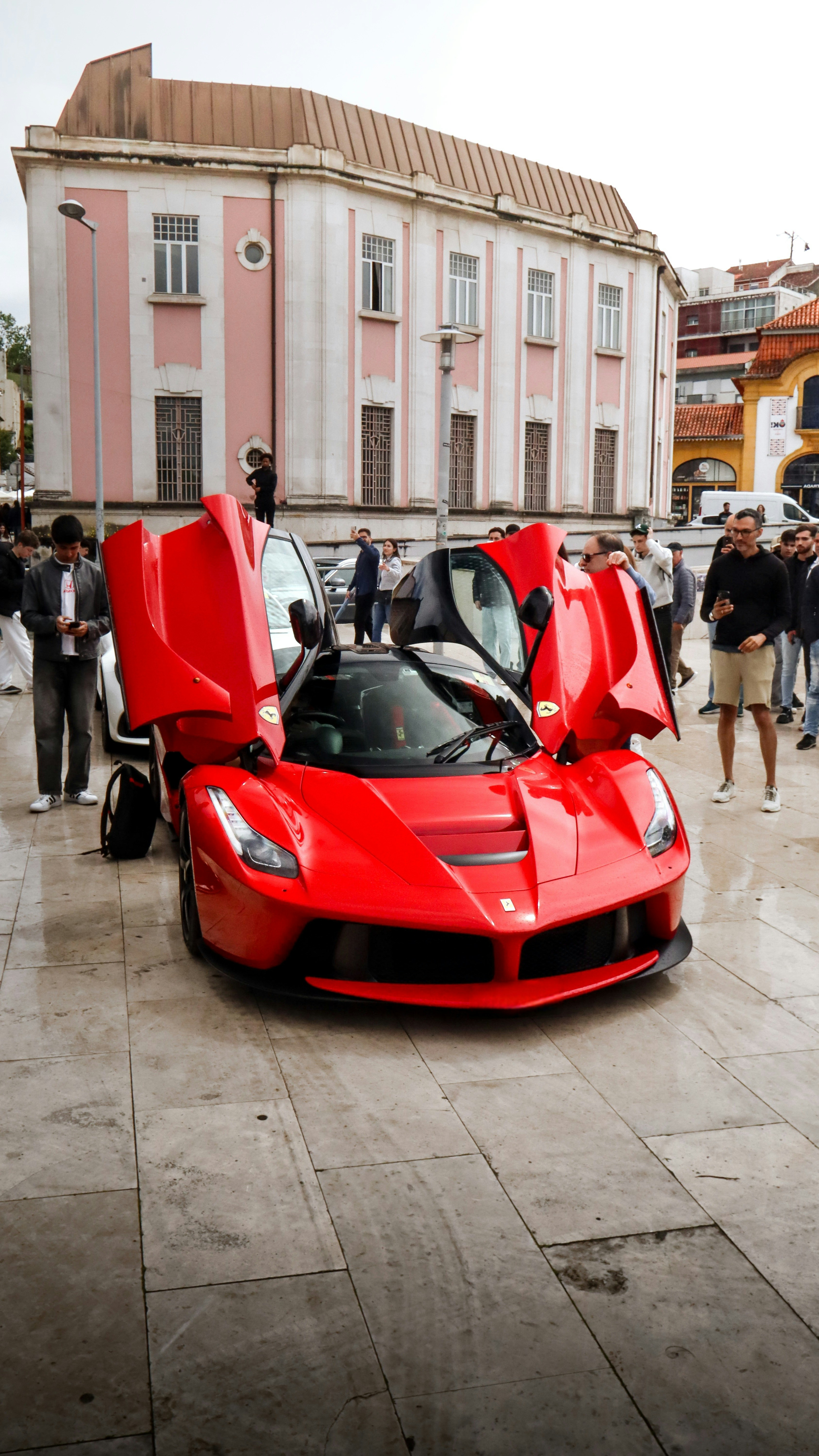 Red ferrari with open doors parked in a city square