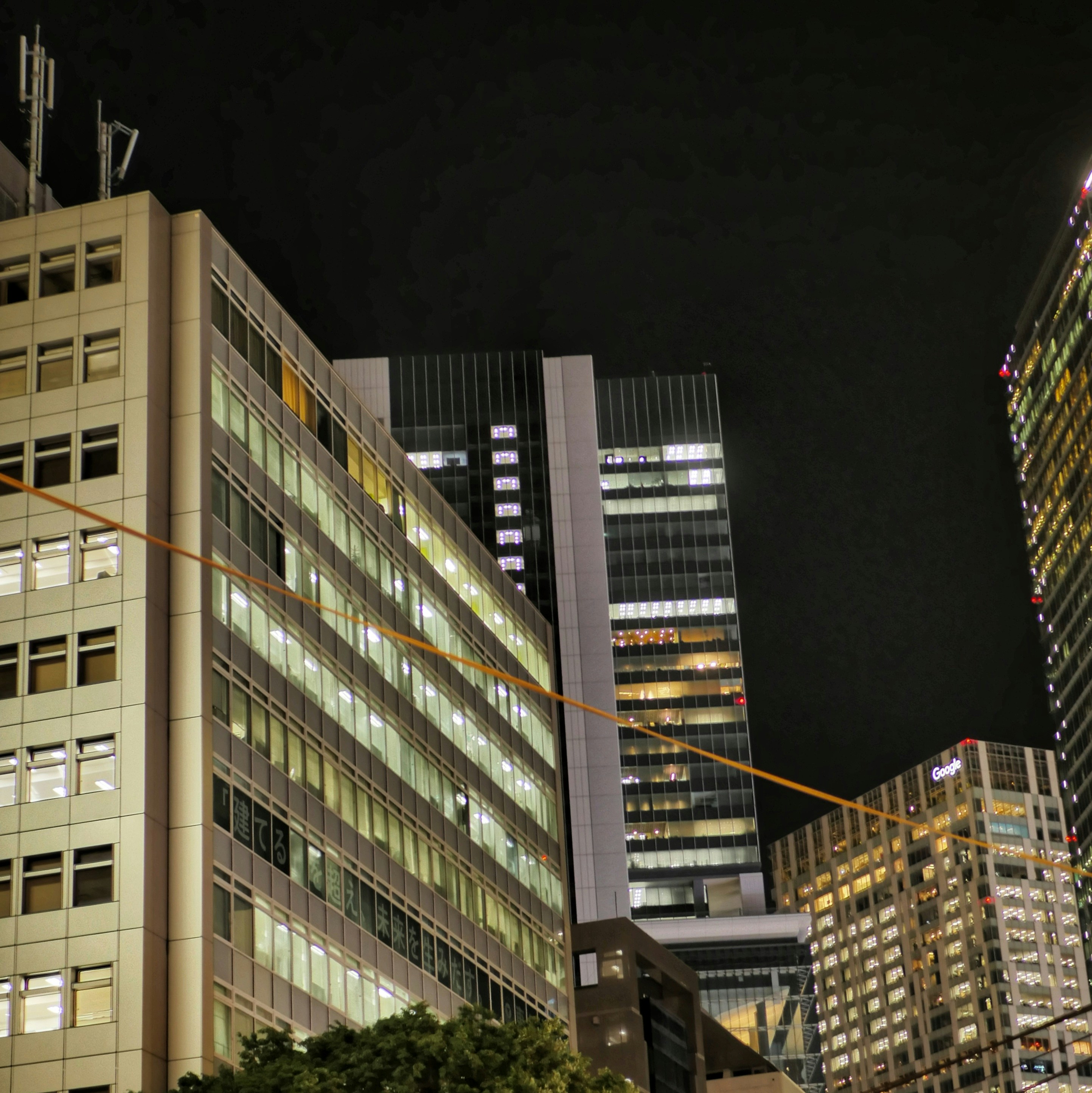 Tall illuminated buildings dominate a dark city skyline at night.