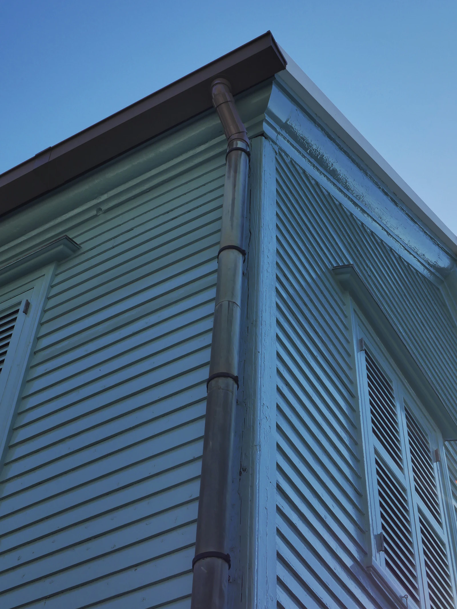 House corner with shutters and a downspout