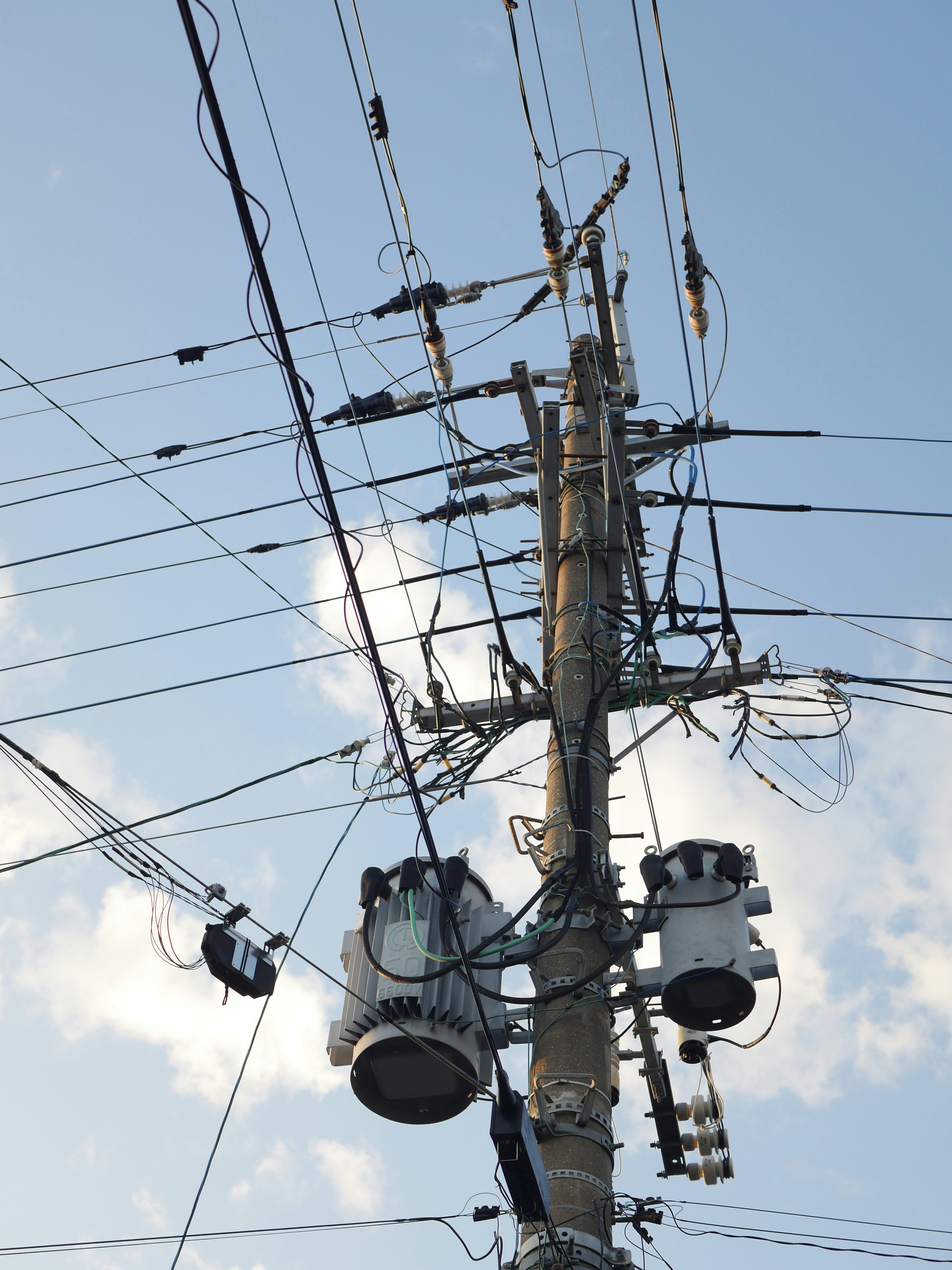 Electrical utility pole with wires and transformers against blue sky.