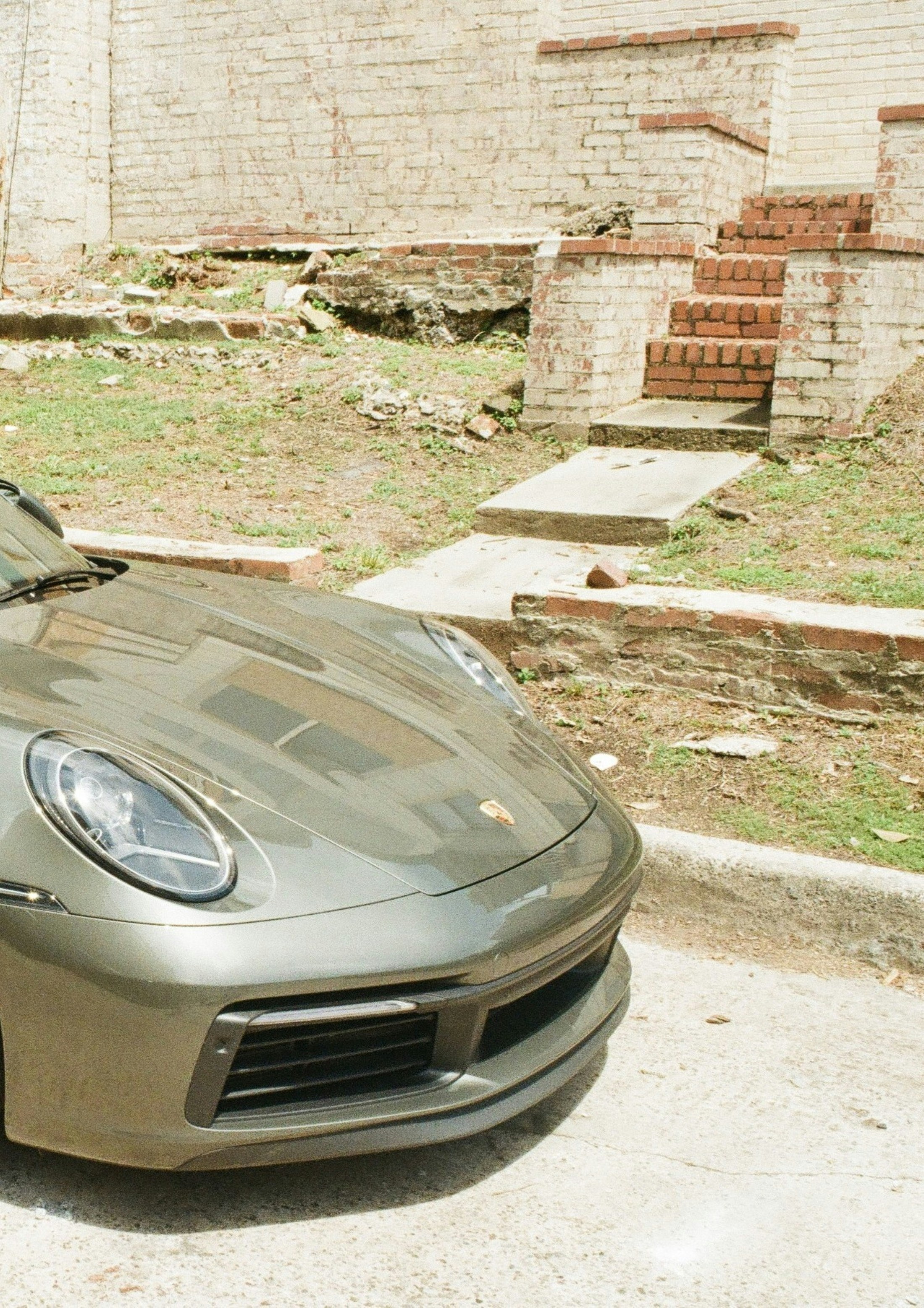 Sleek porsche car parked beside an old brick wall.