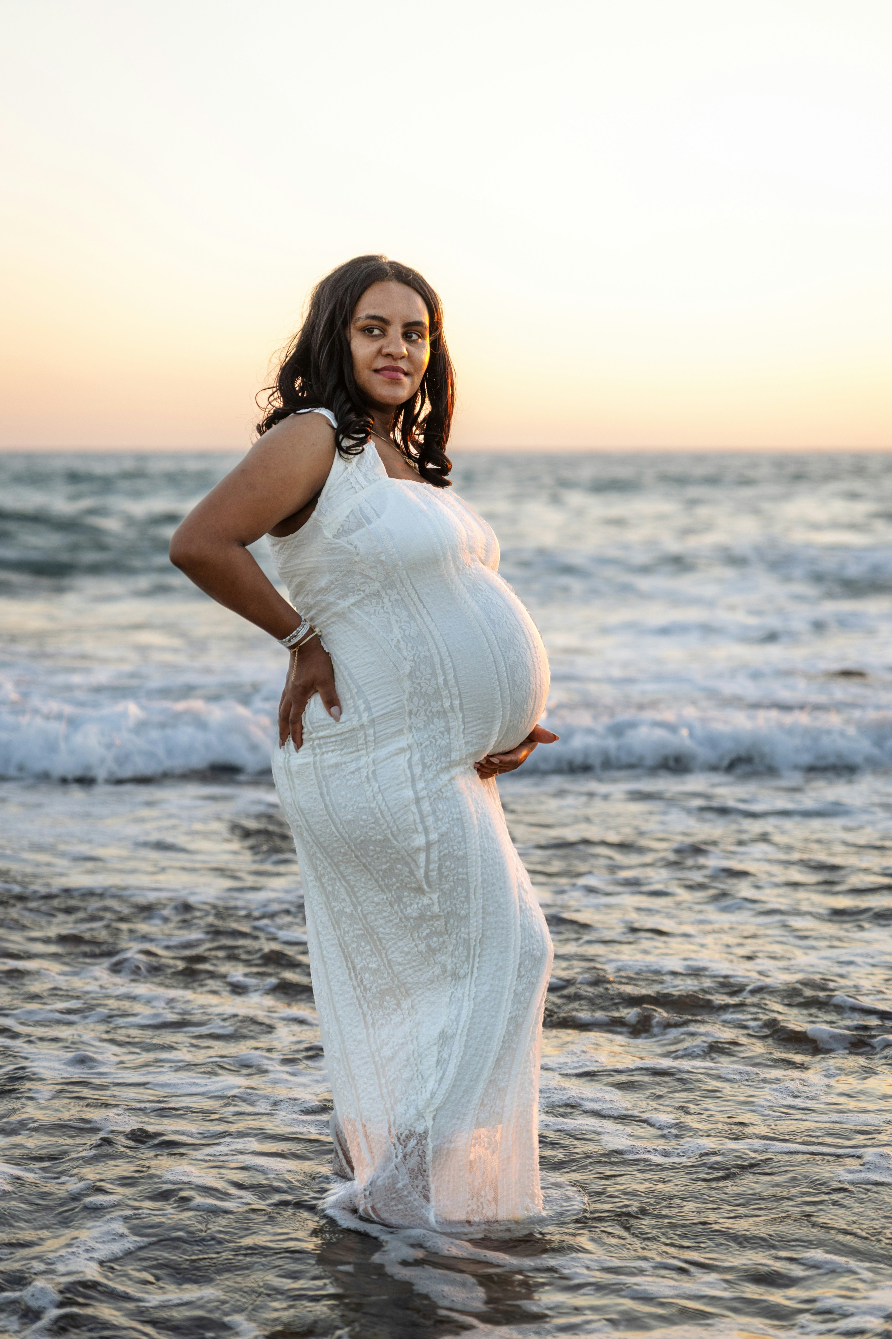 pregnant woman in white dress Freya Maternity Photoshoot Gown sheer short bell sleeves and back The Best White Maternity Dresses