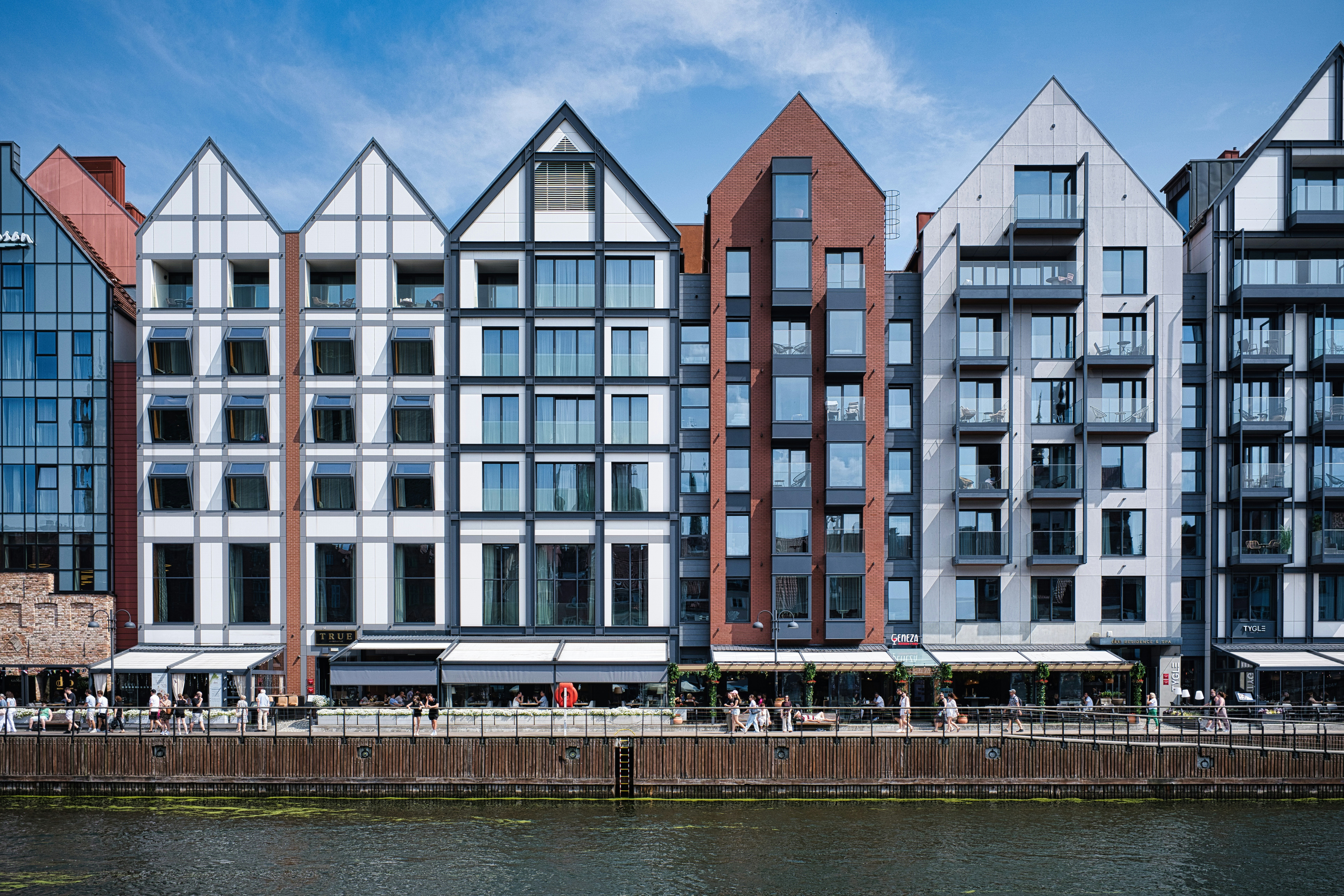 A row of modern gabled buildings along a waterfront.