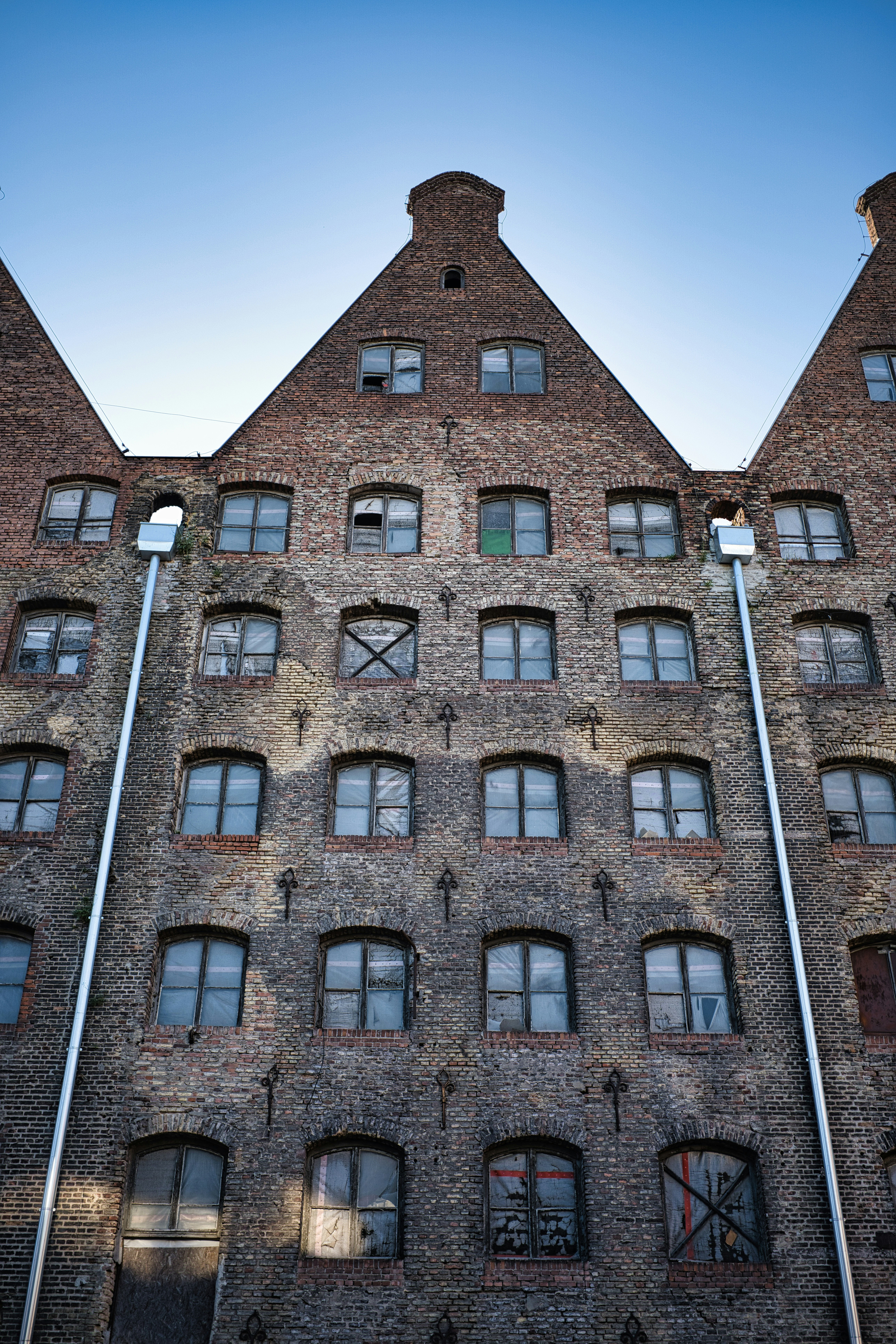 Old brick building with gabled roofs under a blue sky.