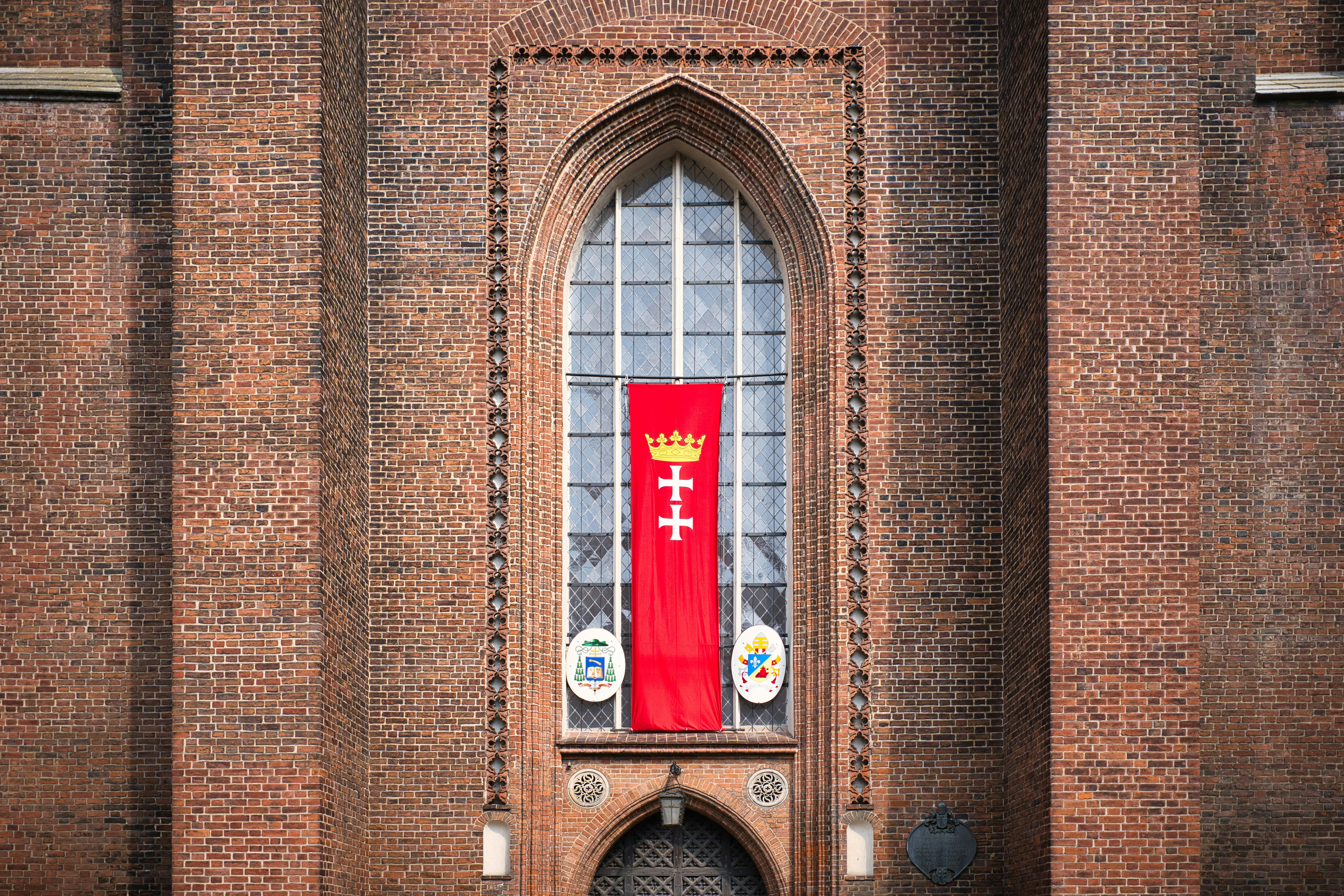Gdańsk banner with crown and cross on a brick facade.