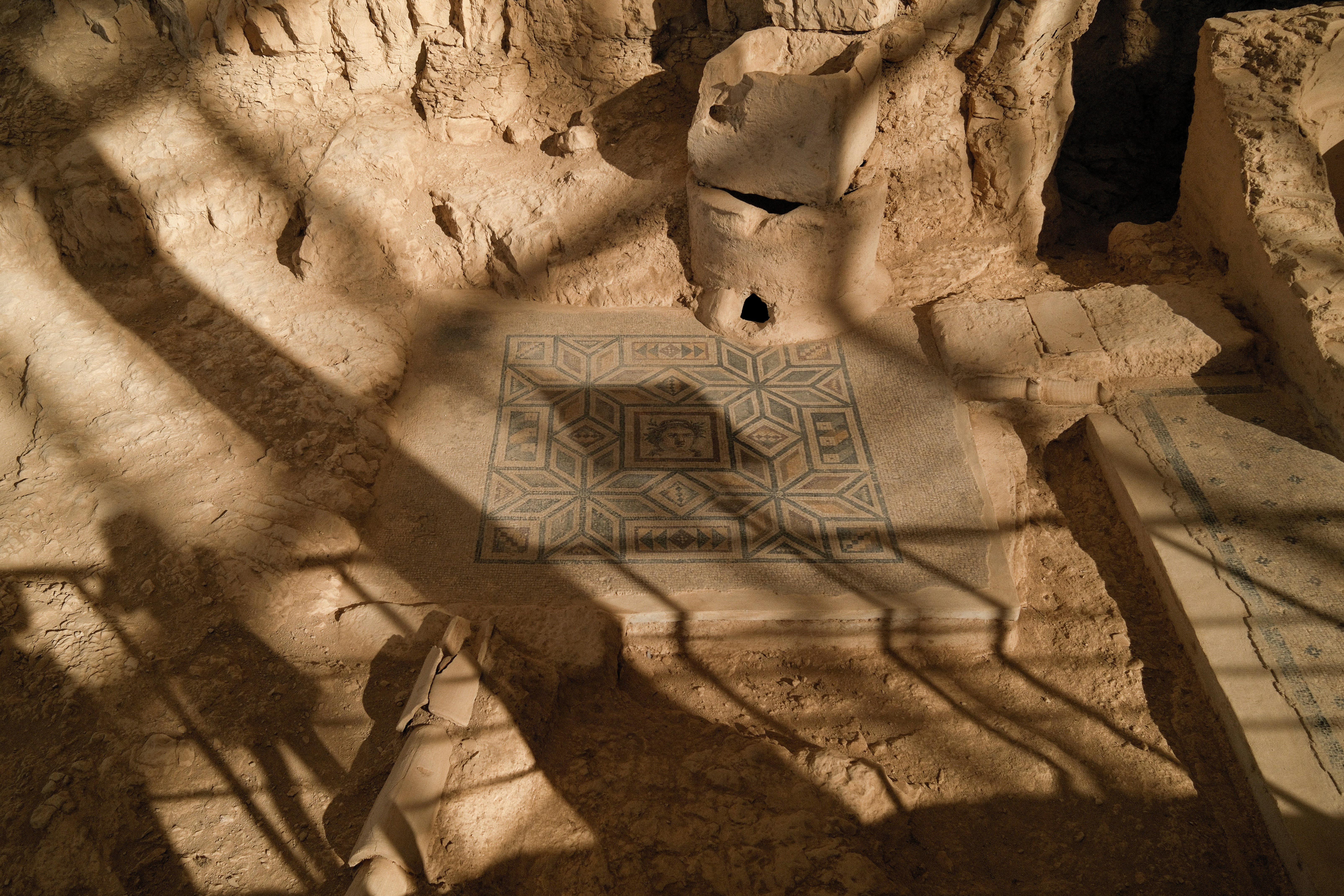 Ancient ruins with a mosaic floor and strong shadows.