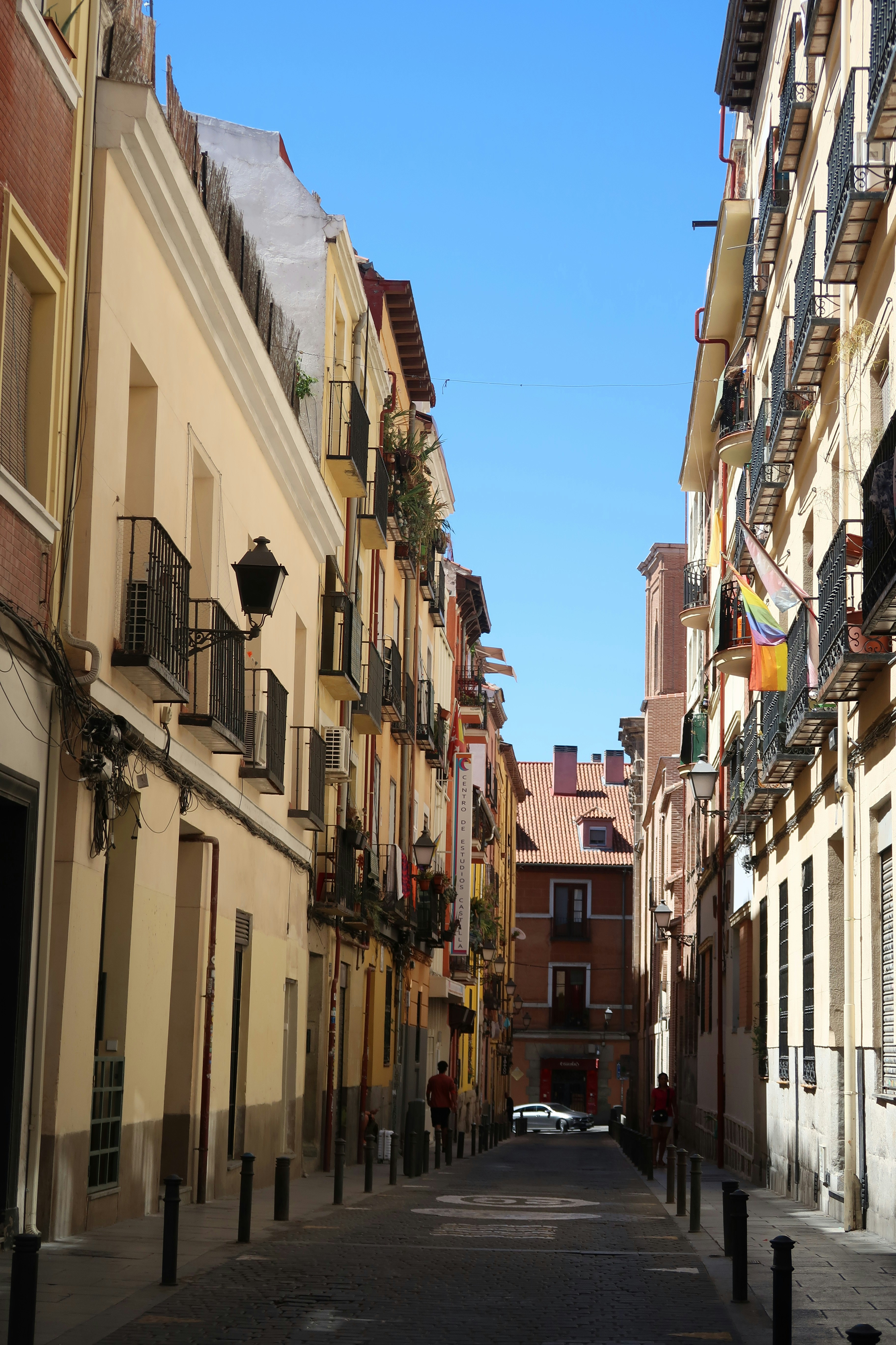 Rua histórica da cidade ladeada por prédios altos sob céu azul.