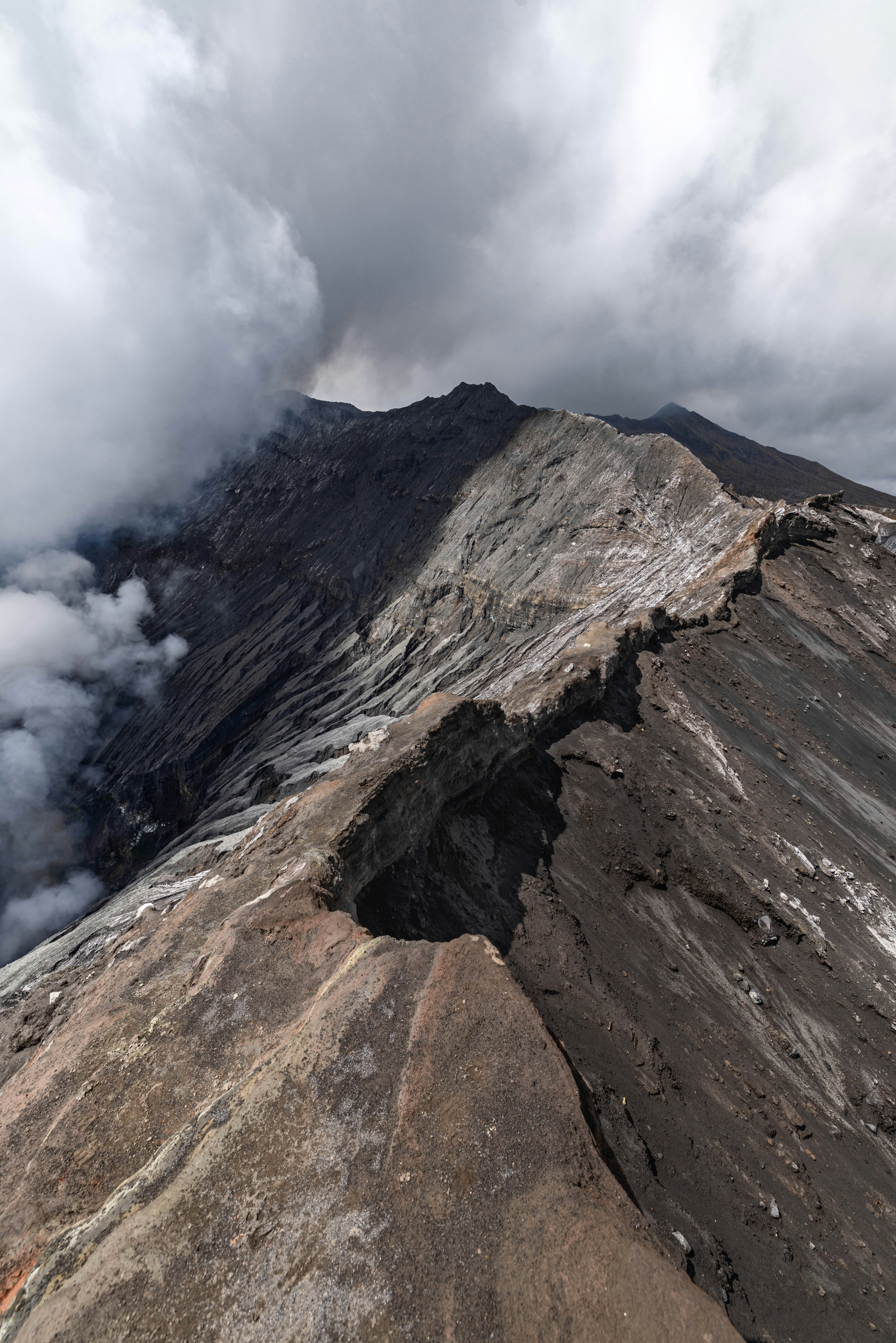 Volcanic crater with dark clouds and smoke rising.