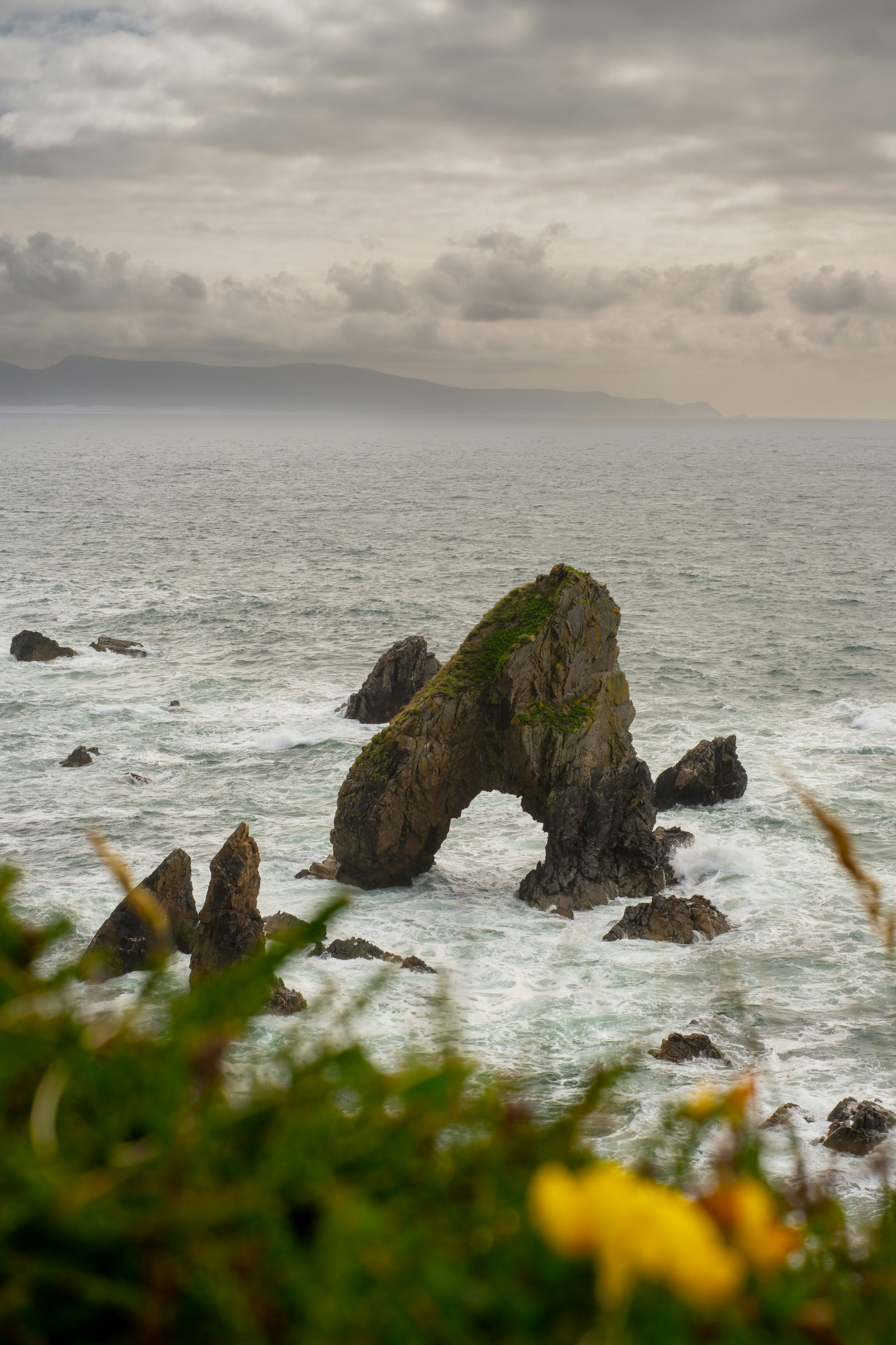 Coastal rock arch in the ocean under a cloudy sky