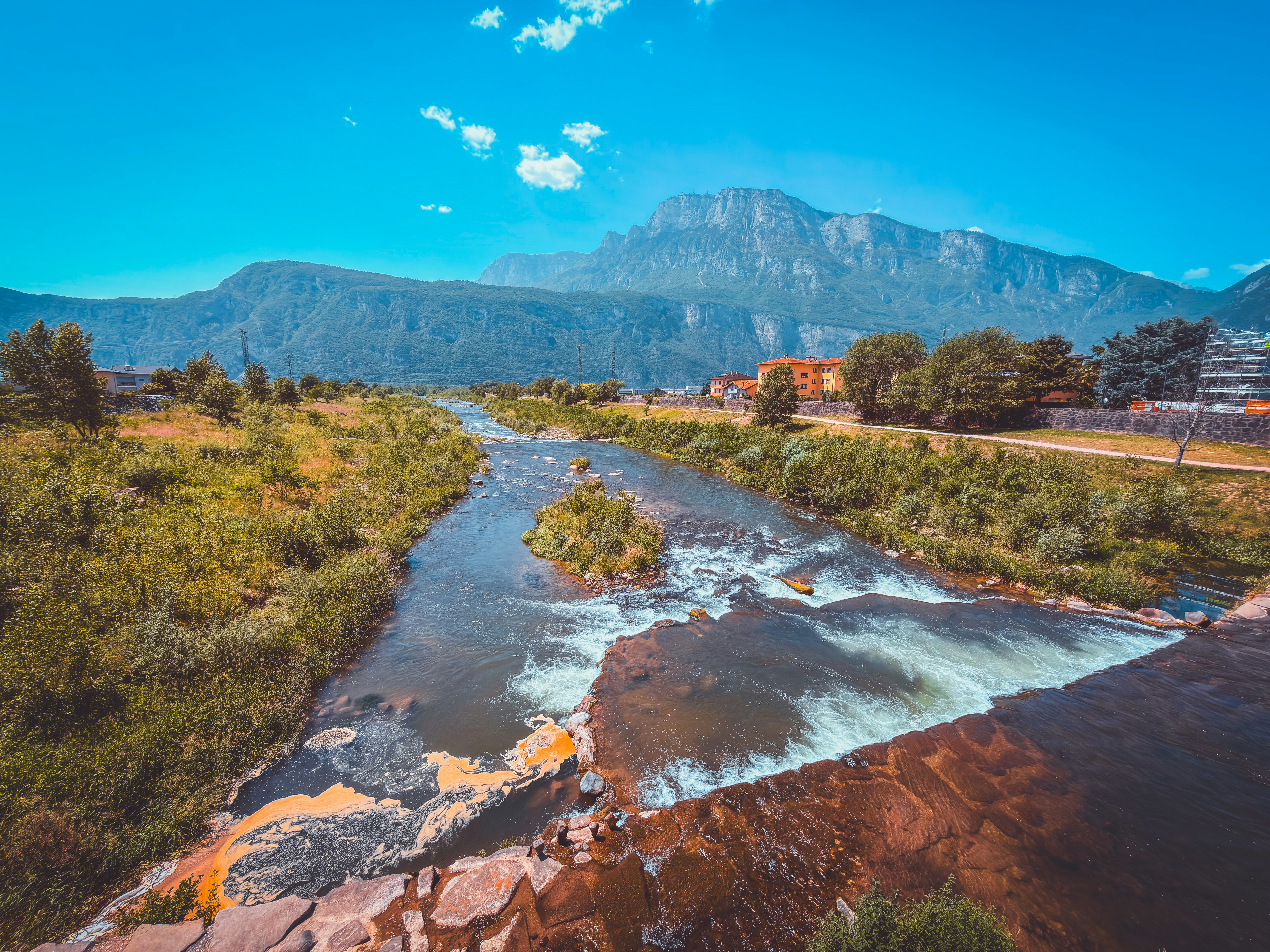 Mountain river with a small waterfall and lush green banks.