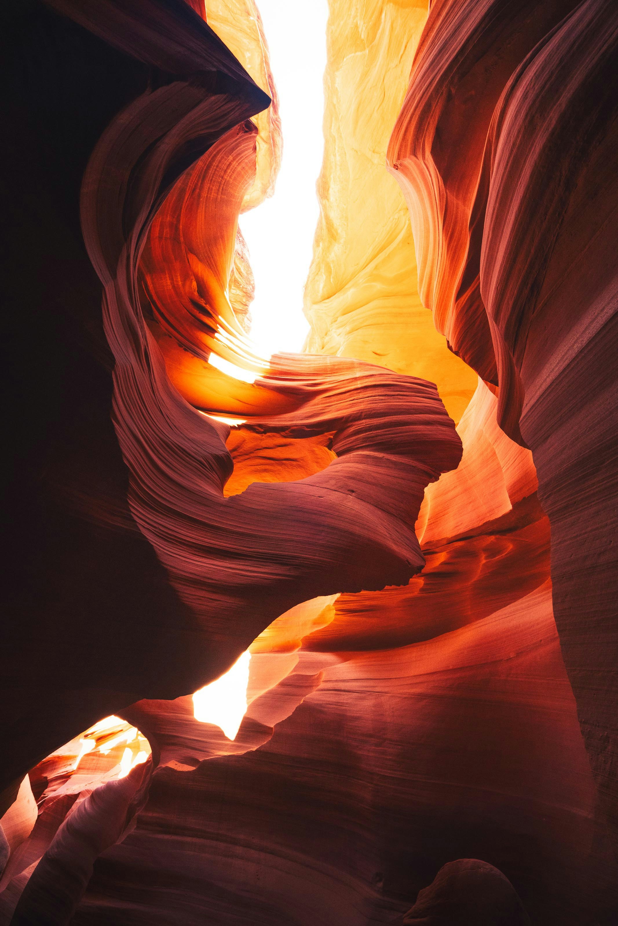 Sunlight illuminates vibrant orange and red slot canyon walls.