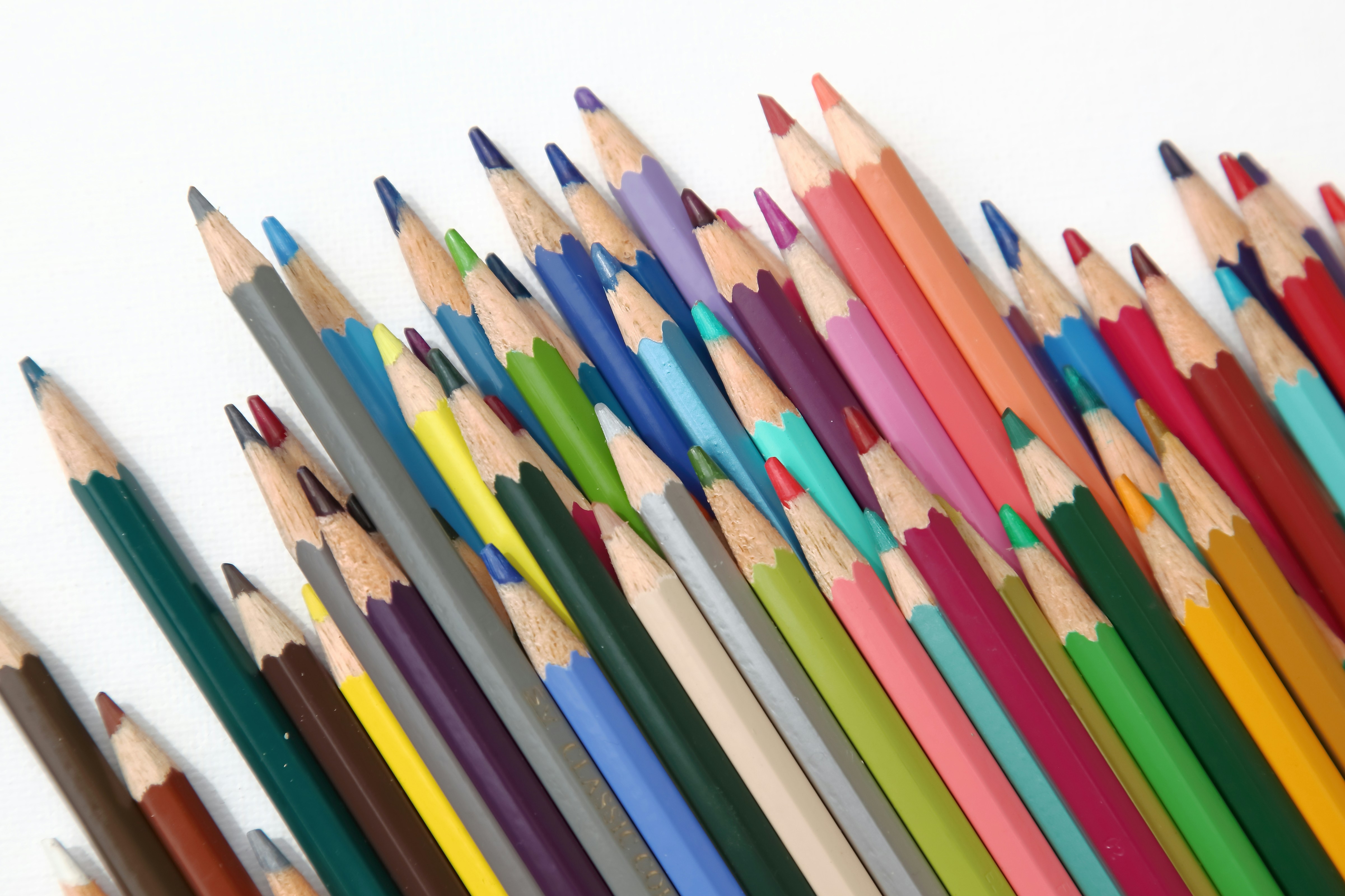A pile of sharpened colorful pencils on a white background.