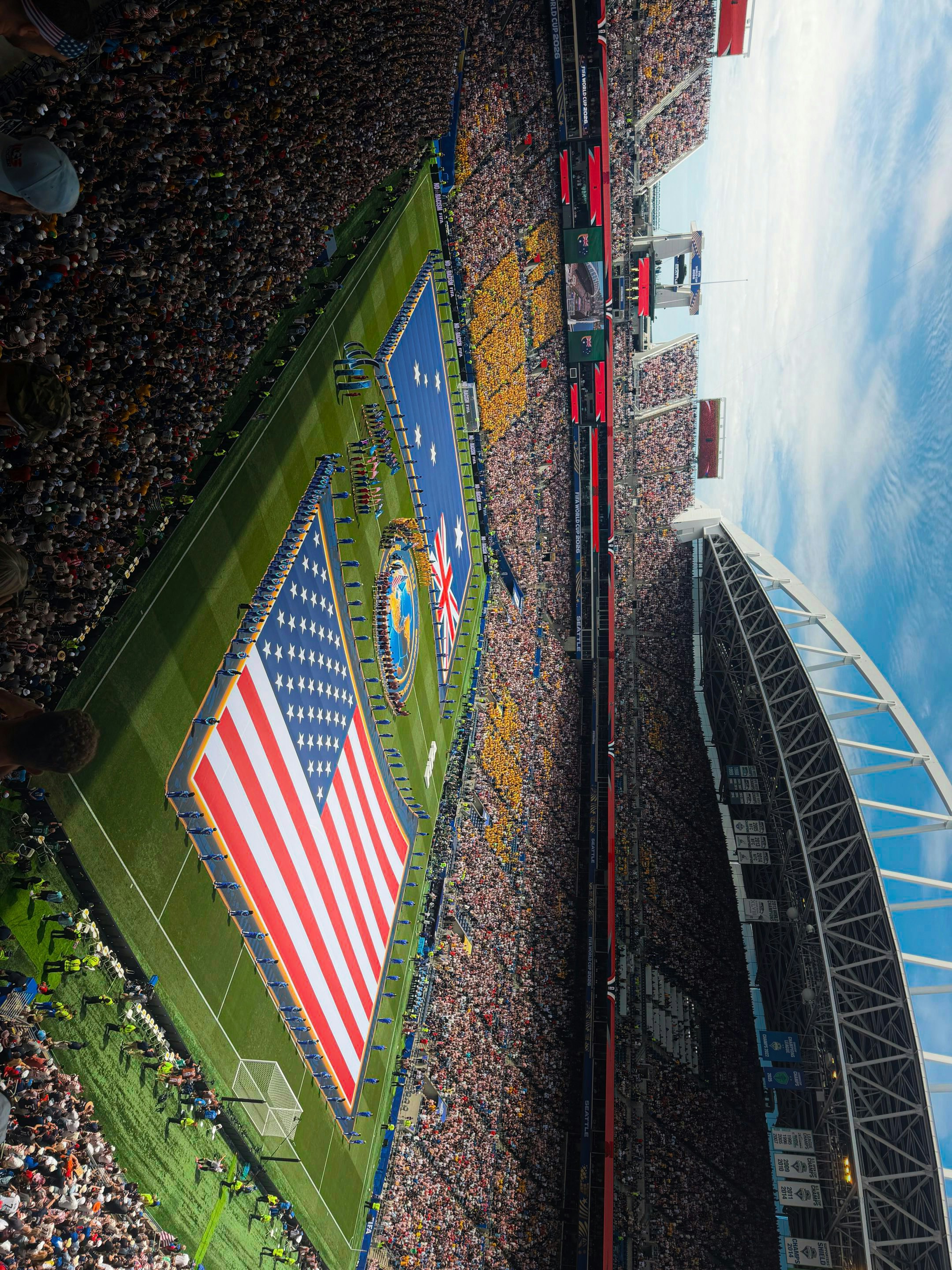 Stadium crowd forms american and australian flags on the field.