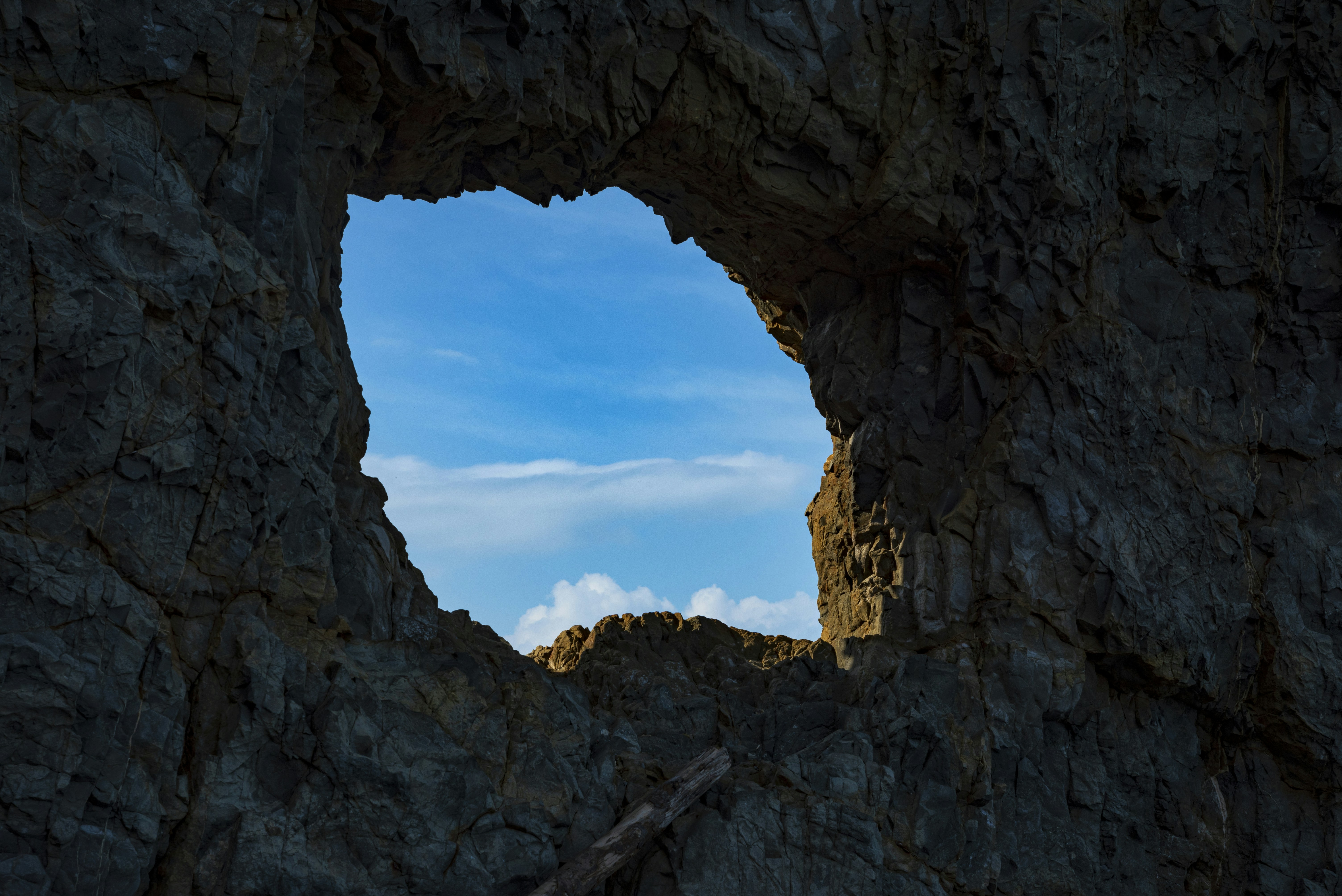 Blue sky seen through a dark rock formation.