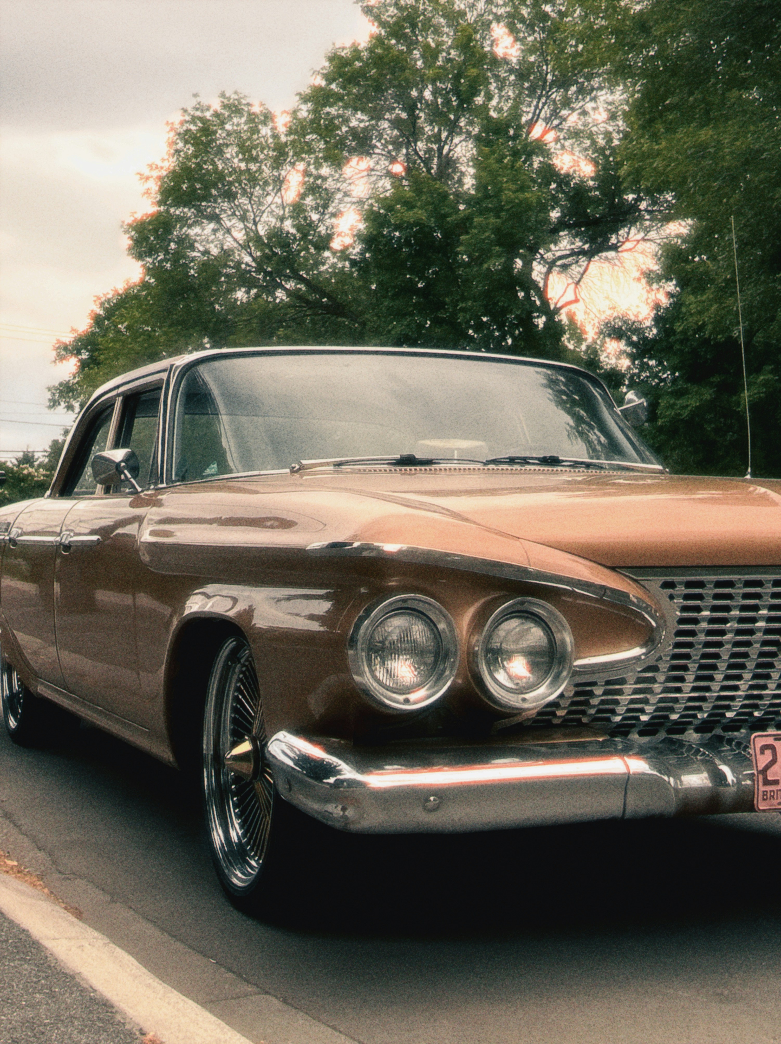 Classic bronze car with prominent headlights and chrome grille