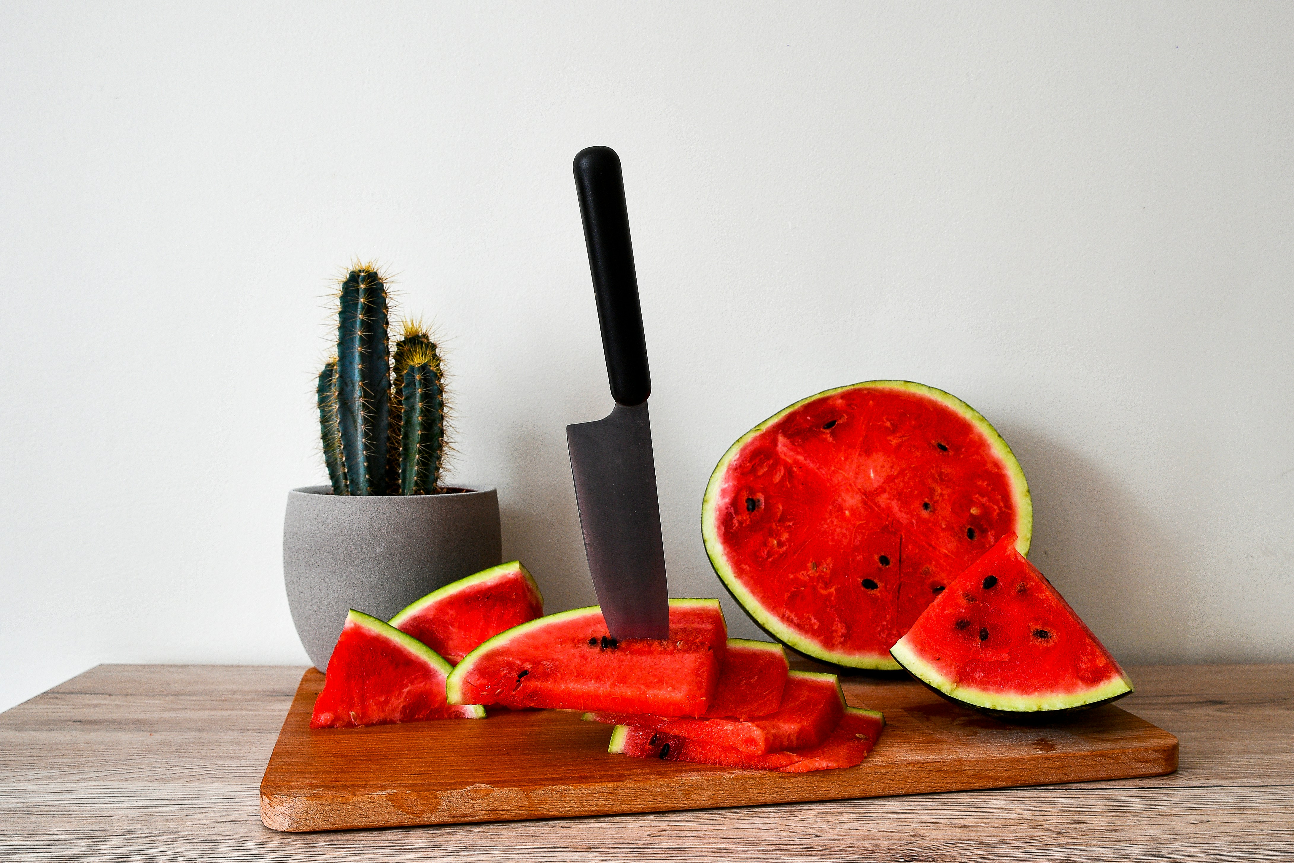 Sliced watermelon and knife on a cutting board with cactus