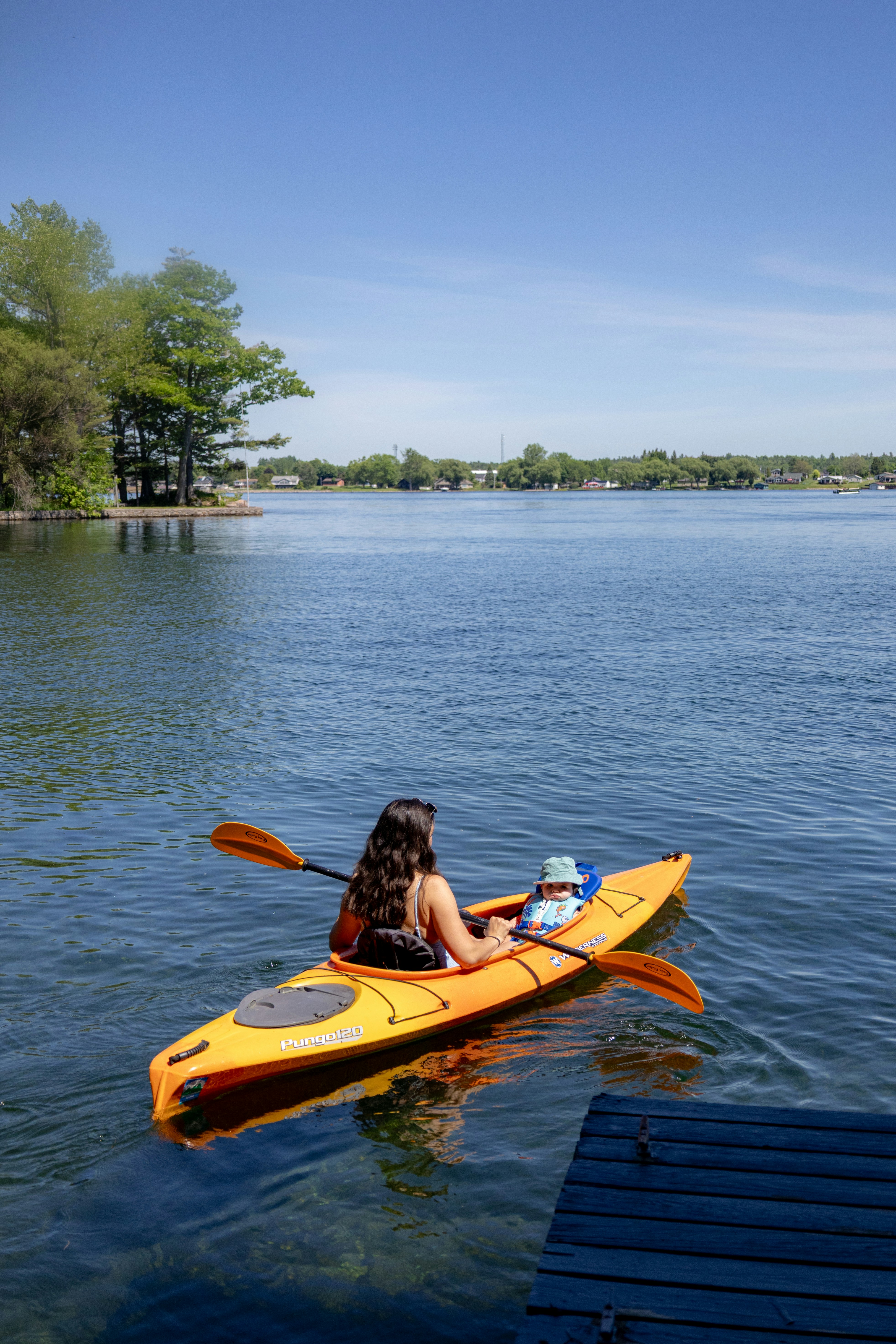 Une femme et un enfant font du kayak sur un lac ensoleillé.