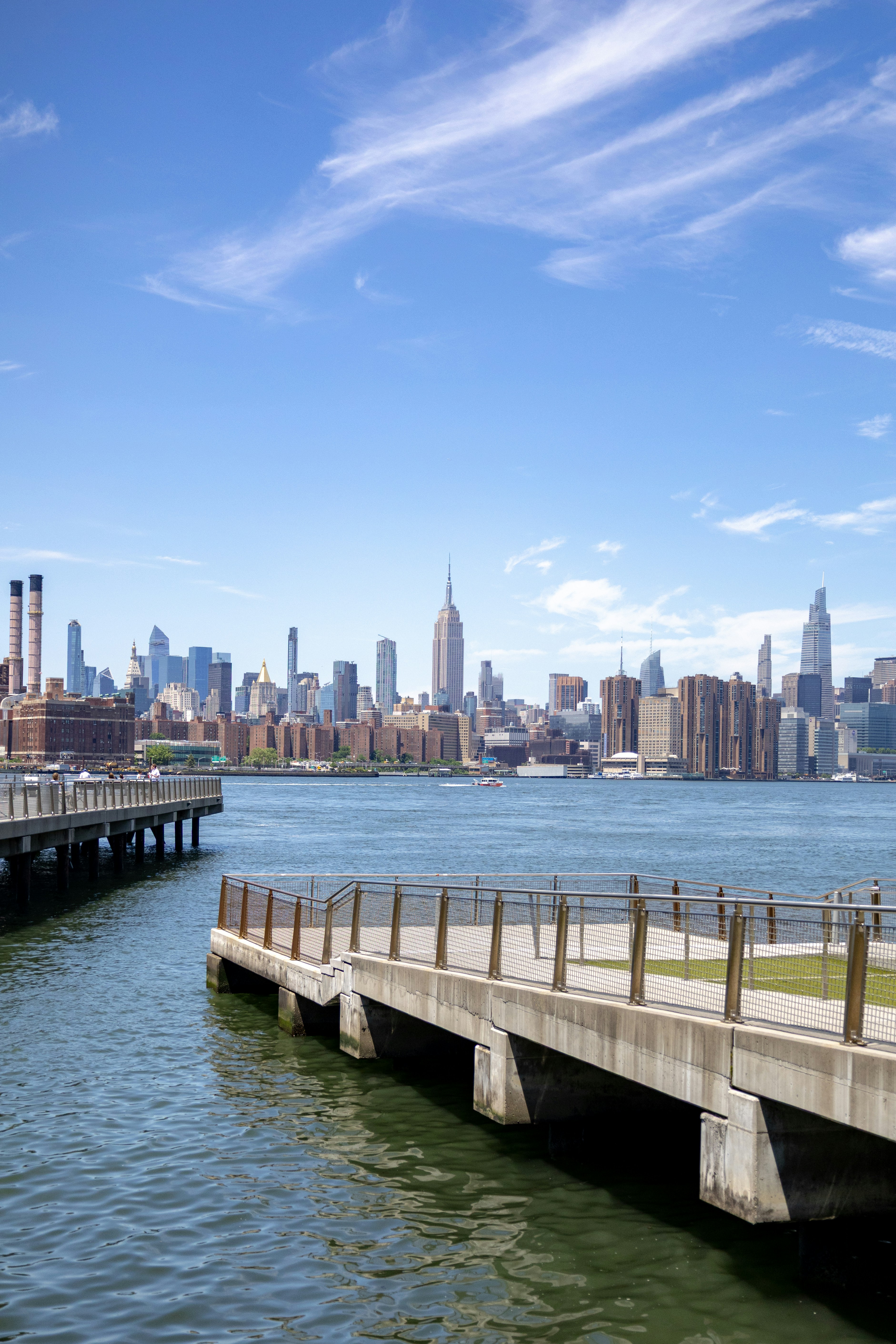 La silhouette de Manhattan avec des jetées au-dessus de l’eau sous un ciel bleu.