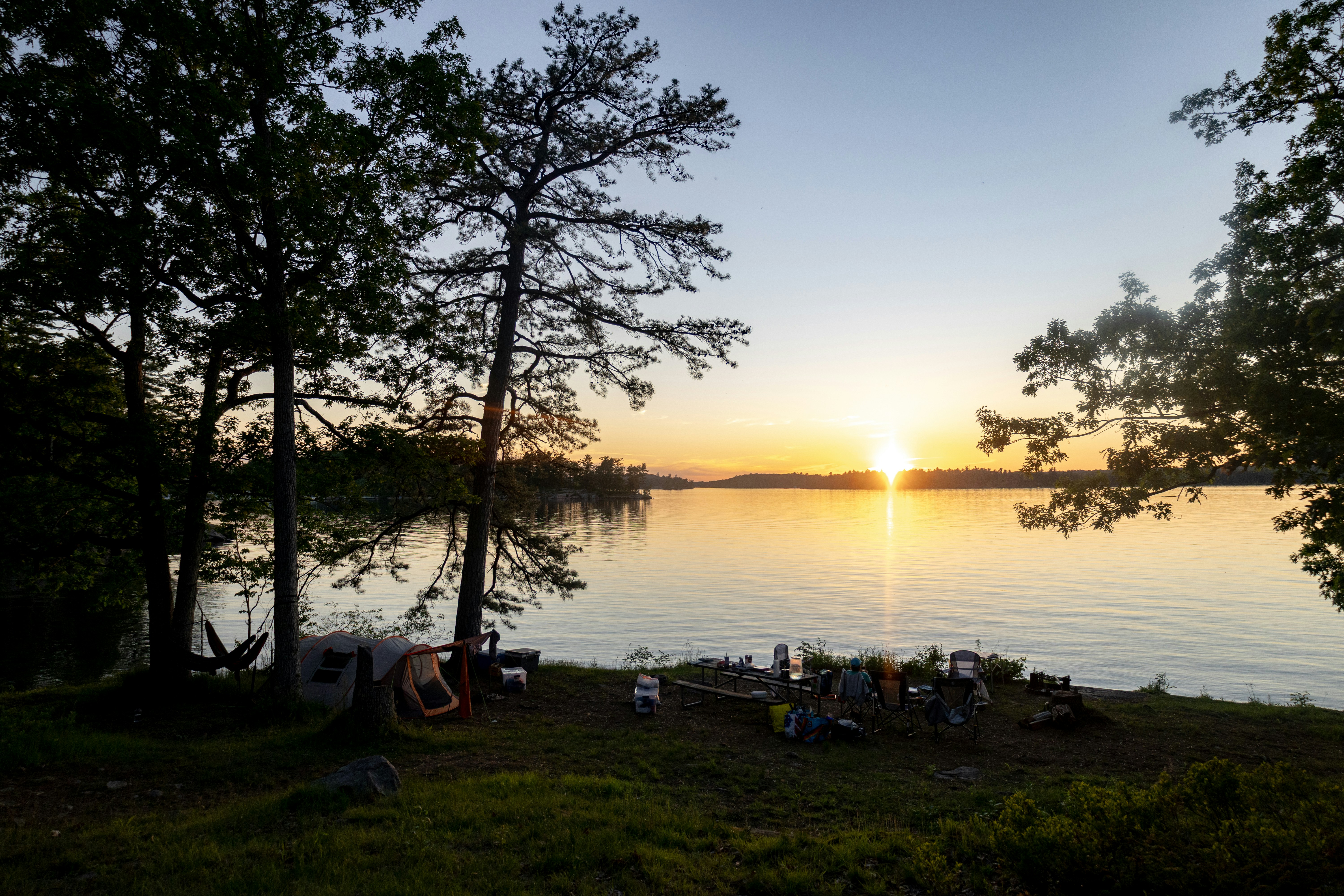 Camping au bord du lac au coucher du soleil avec un groupe d’amis.