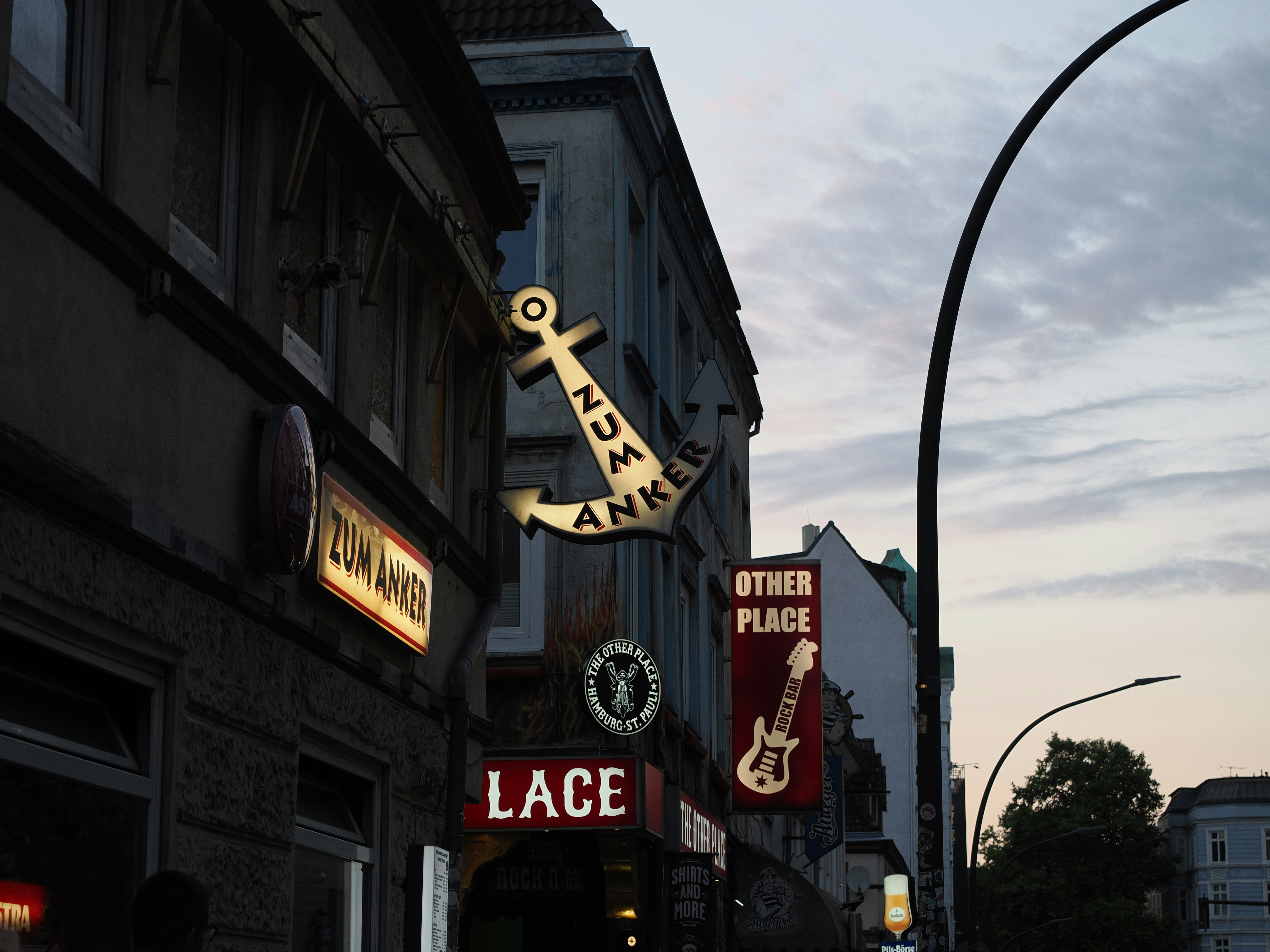 Illuminated street signs on buildings at dusk.