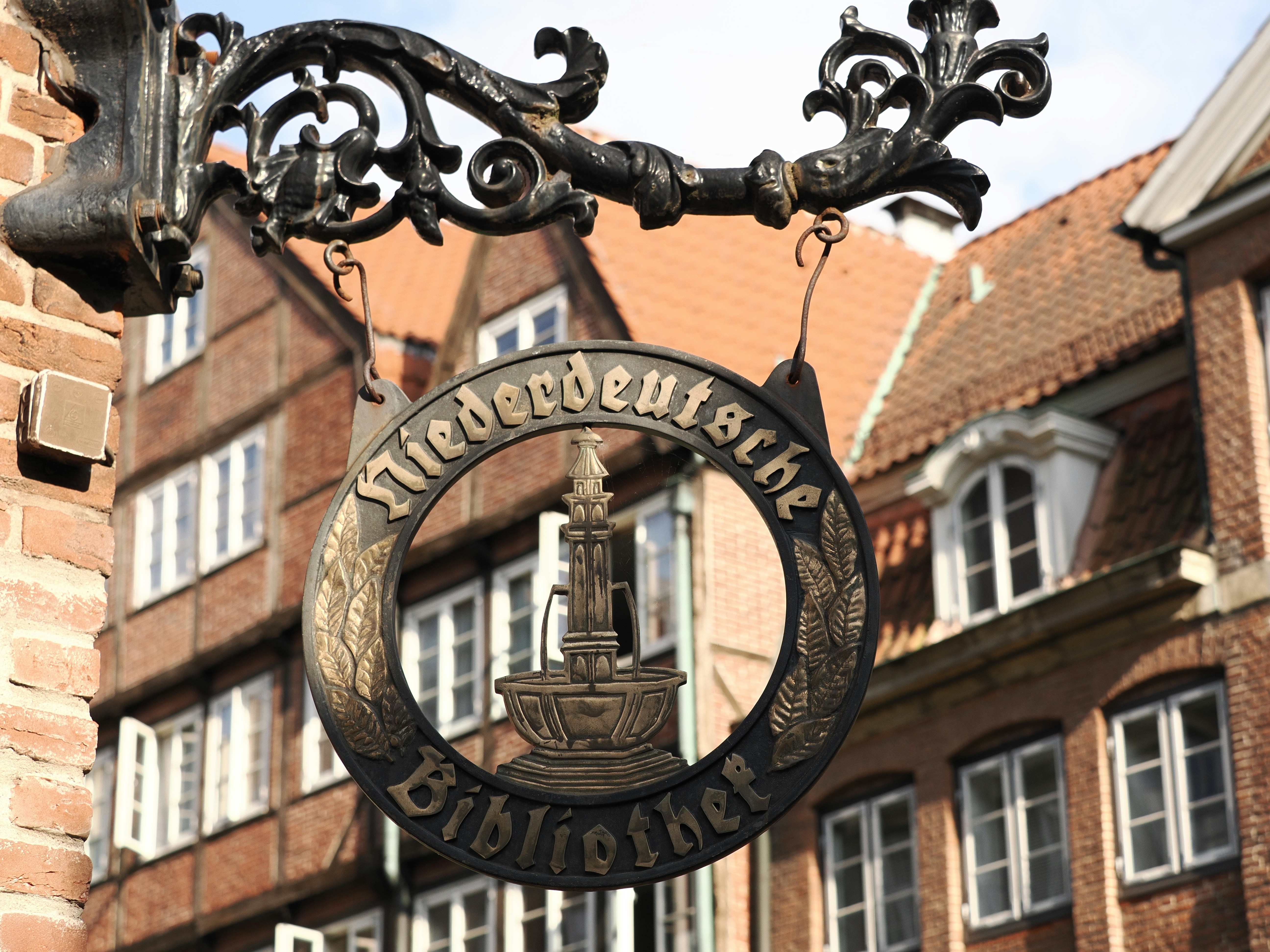 Placa ornamentada "niederdeutsche bibliothek" em um edifício histórico.
