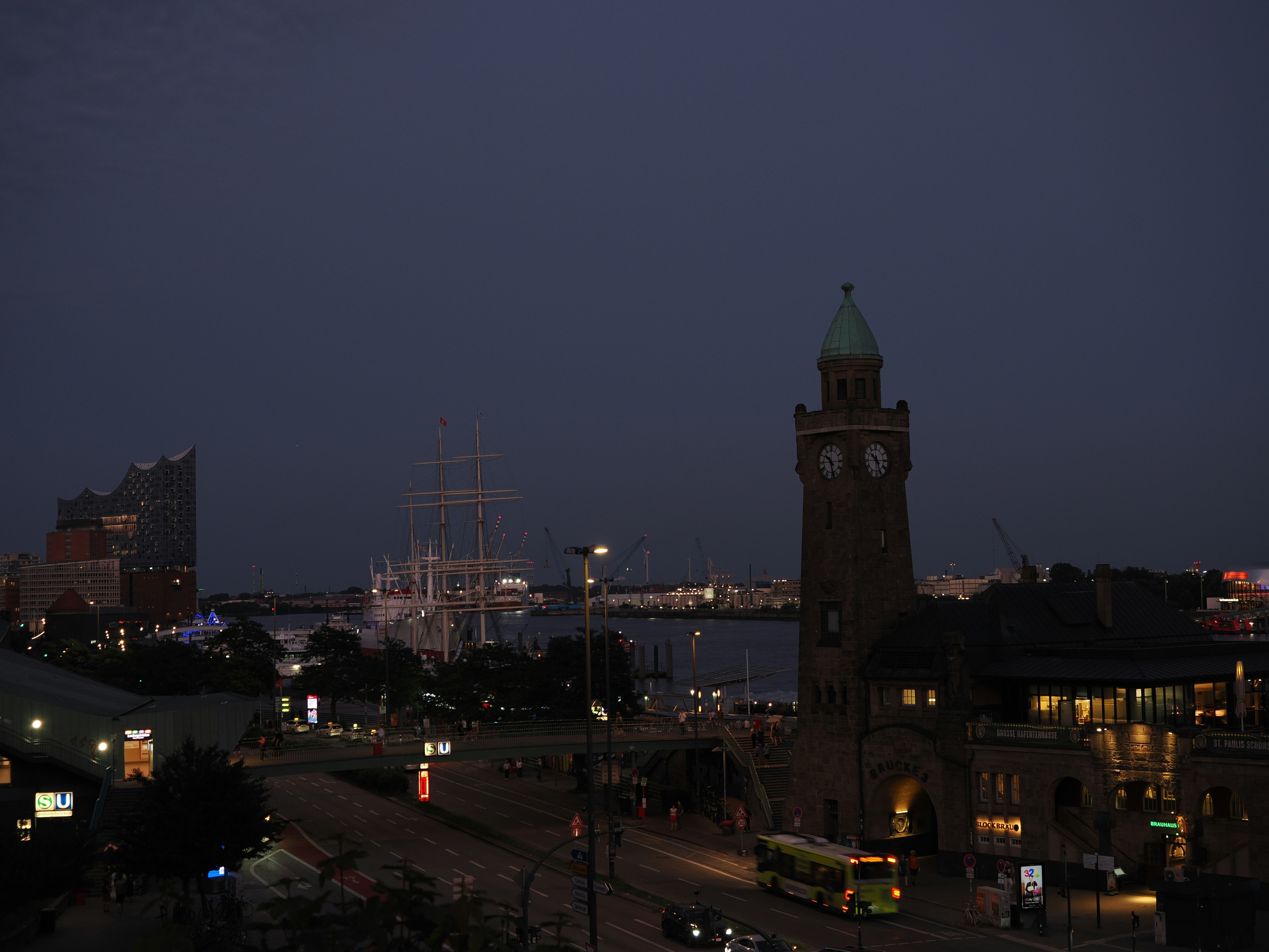 Historic clock tower overlooks a bustling harbor at night.