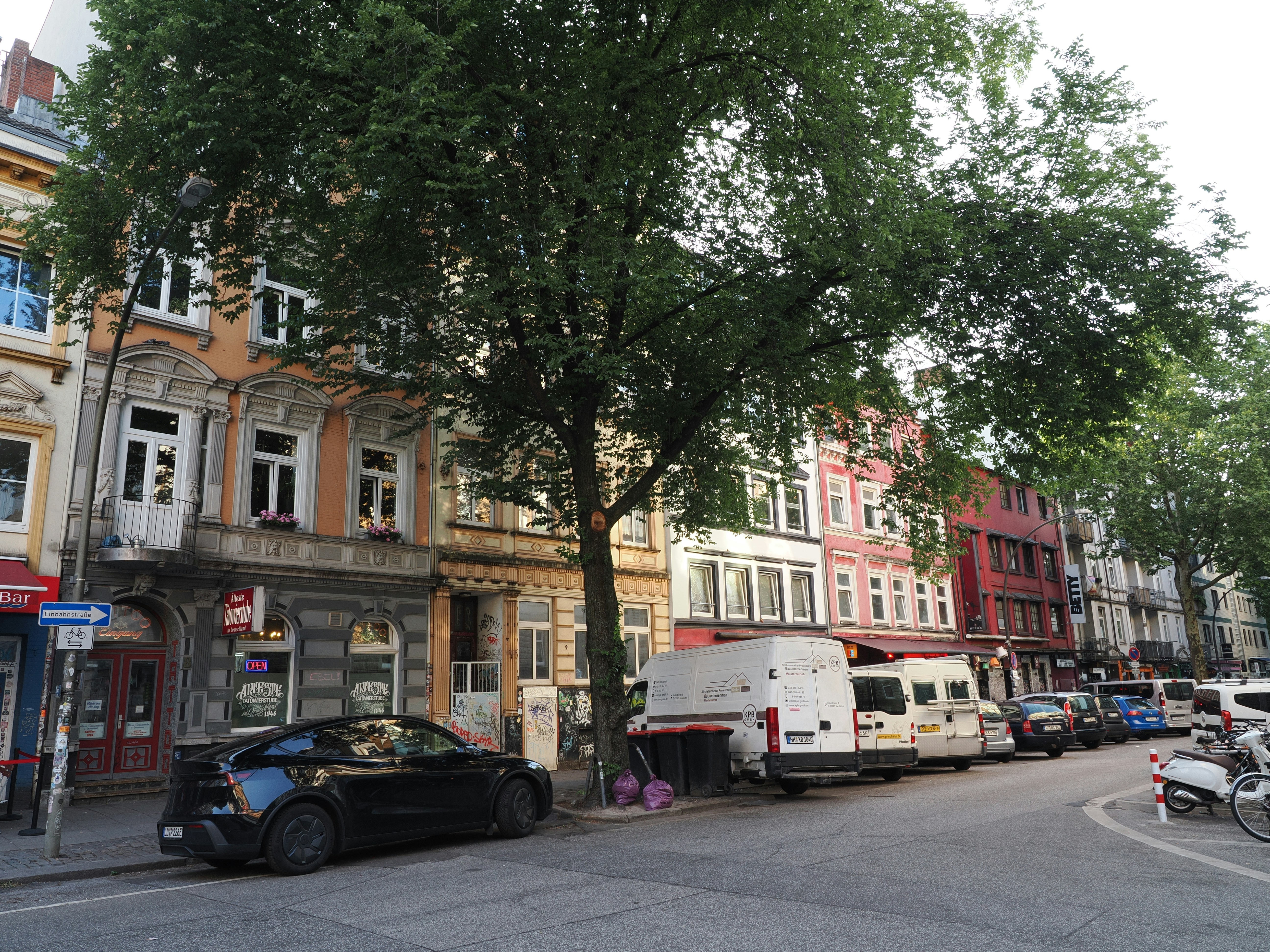 Colorful historic buildings line an urban street with parked vehicles.