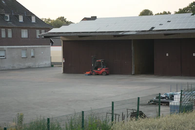 Red forklift parked outside a building with solar panels.