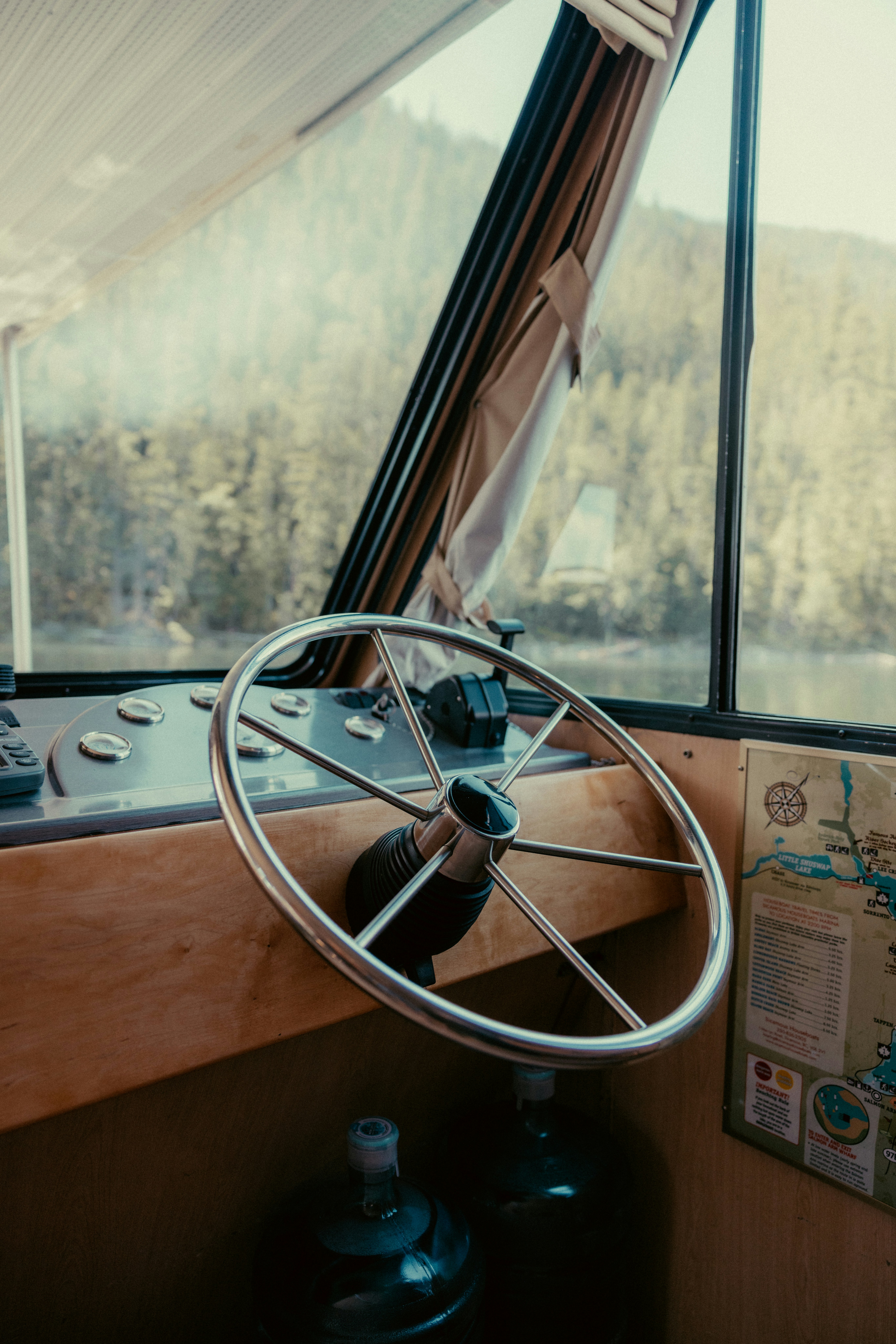 Boat cockpit with steering wheel and scenic mountain view.
