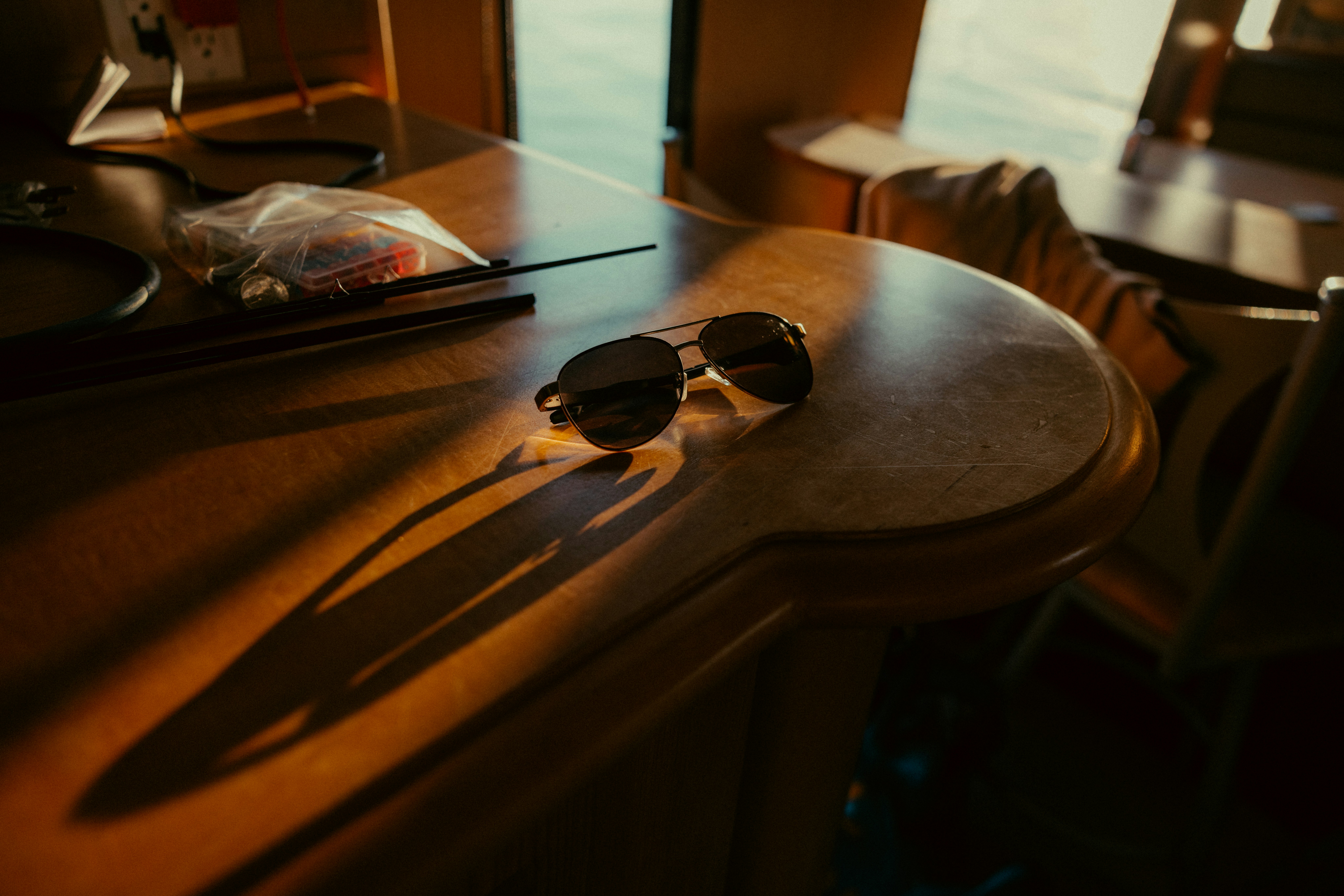 Dark sunglasses cast long shadows on a wooden surface.