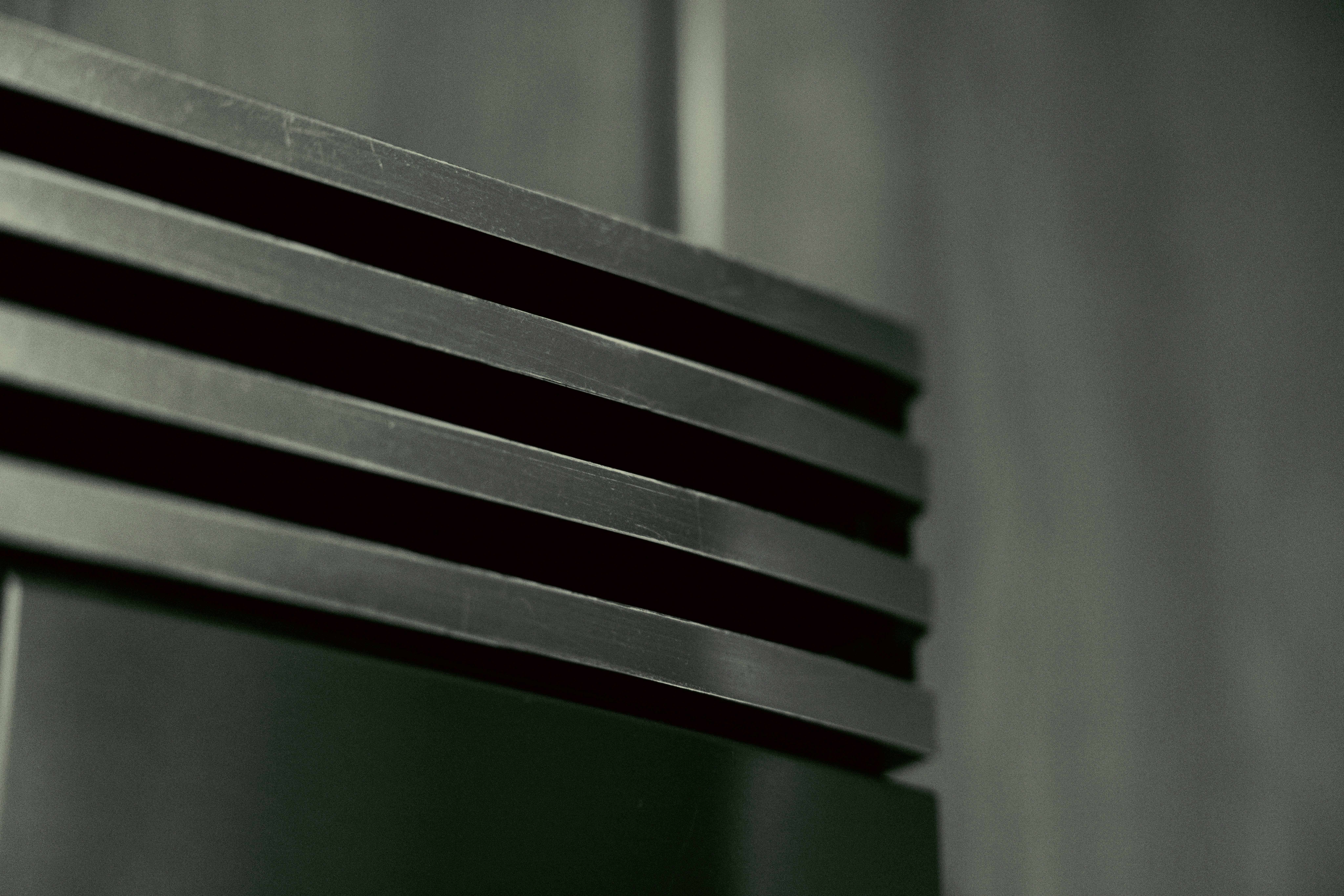 Textured dark gray metal surface with horizontal grooves.