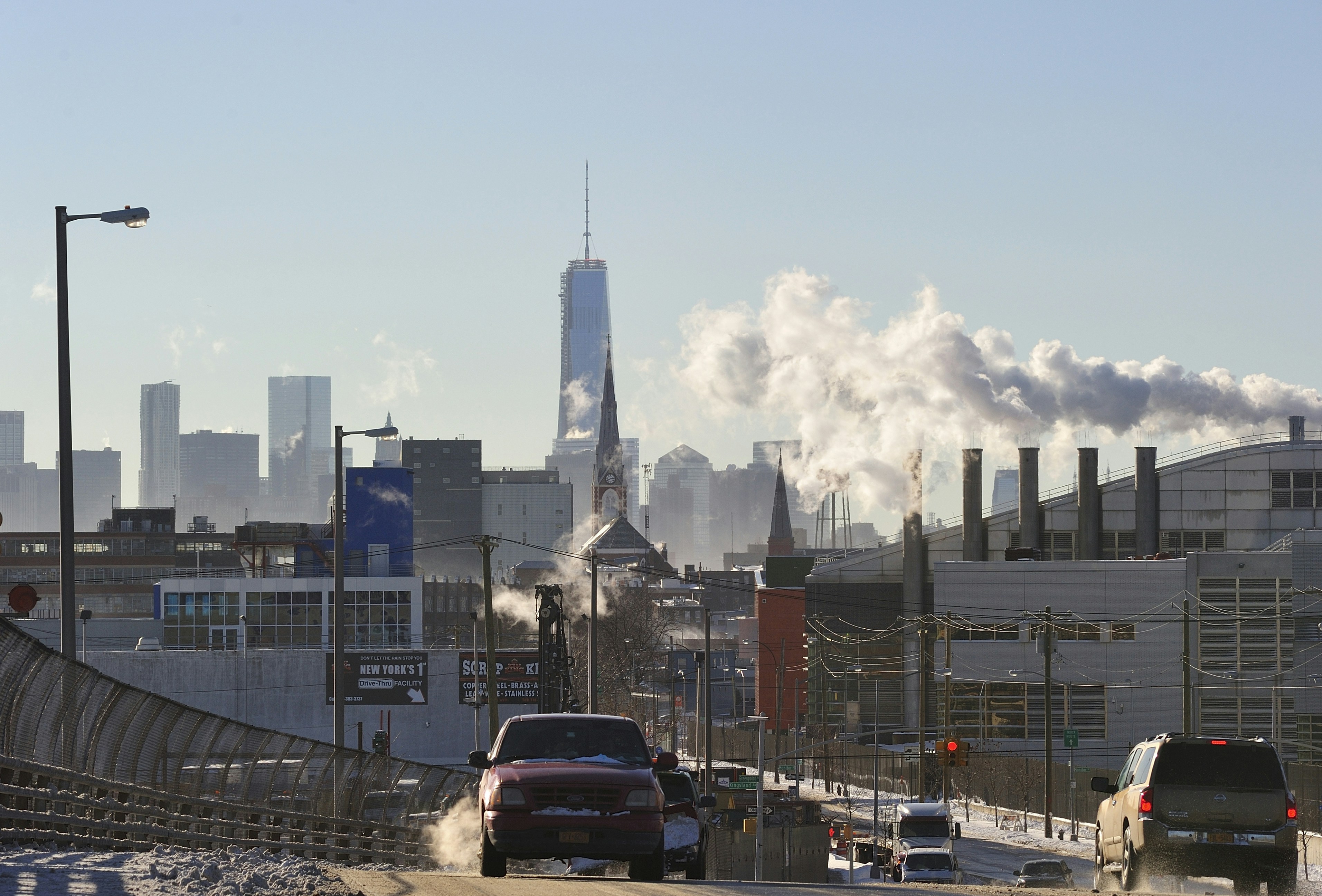 Snowy road with city skyline, freedom tower, and rising steam.