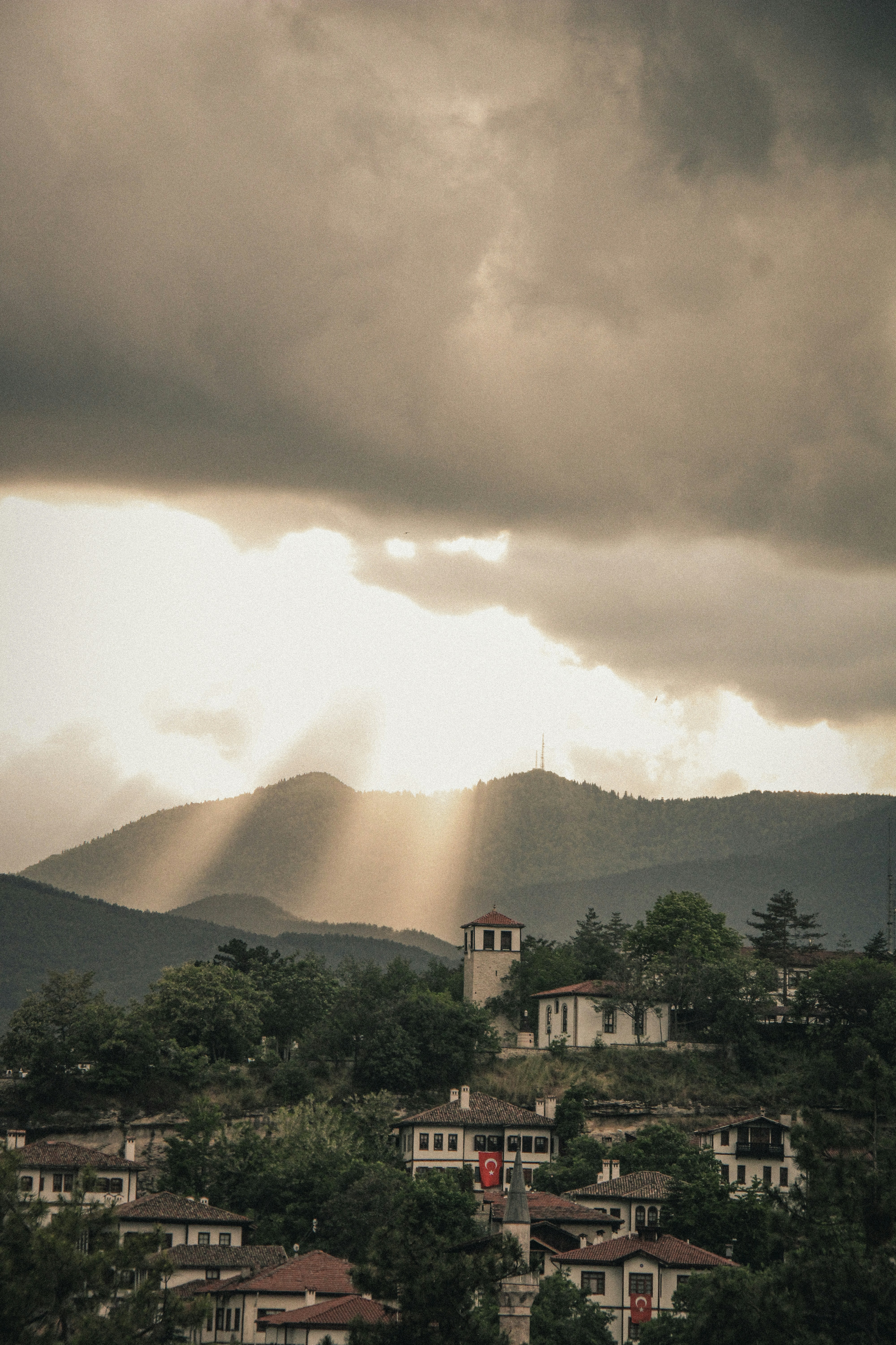Sun rays illuminate a traditional village nestled in mountains.