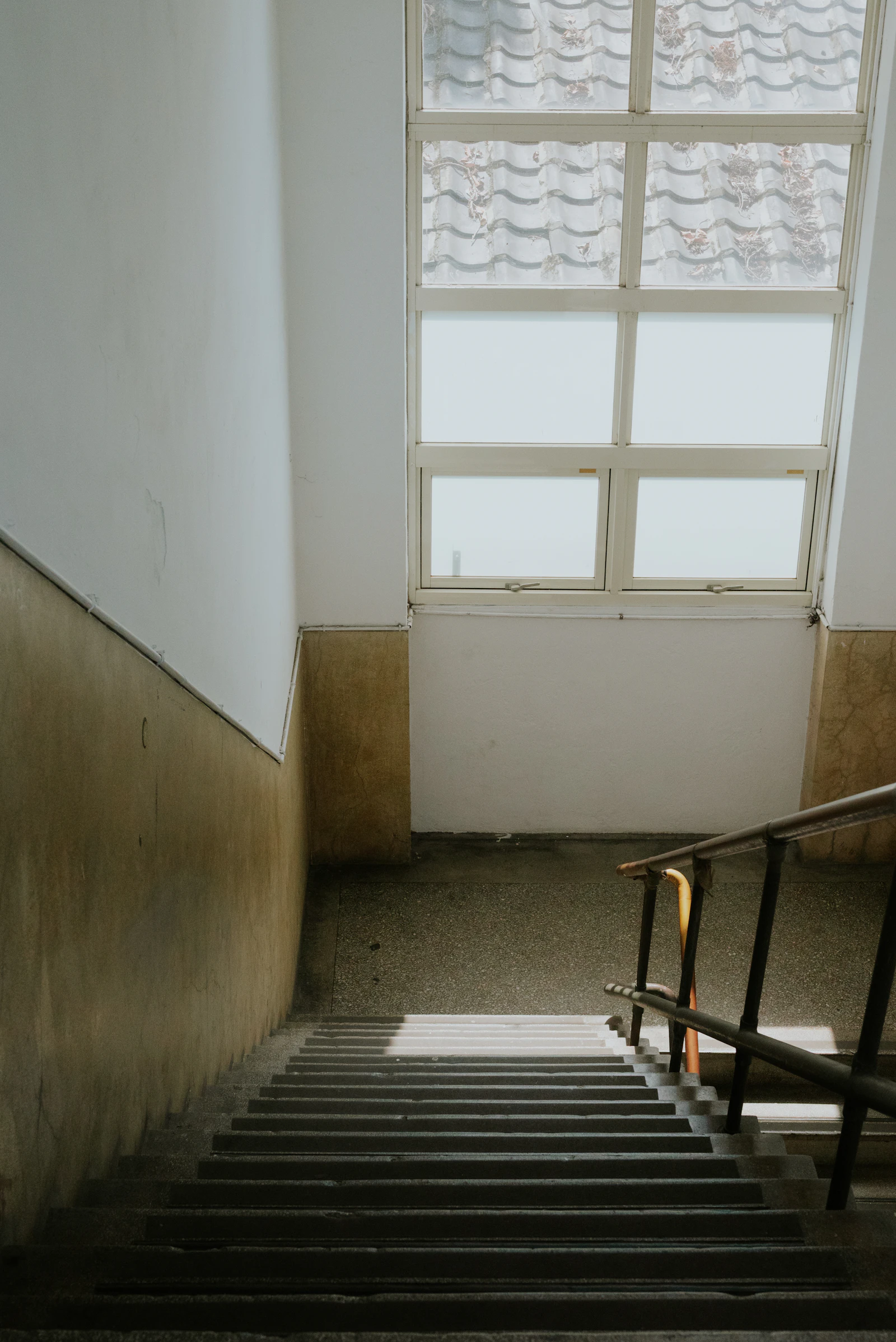 Concrete staircase with a metal railing leading to a large window