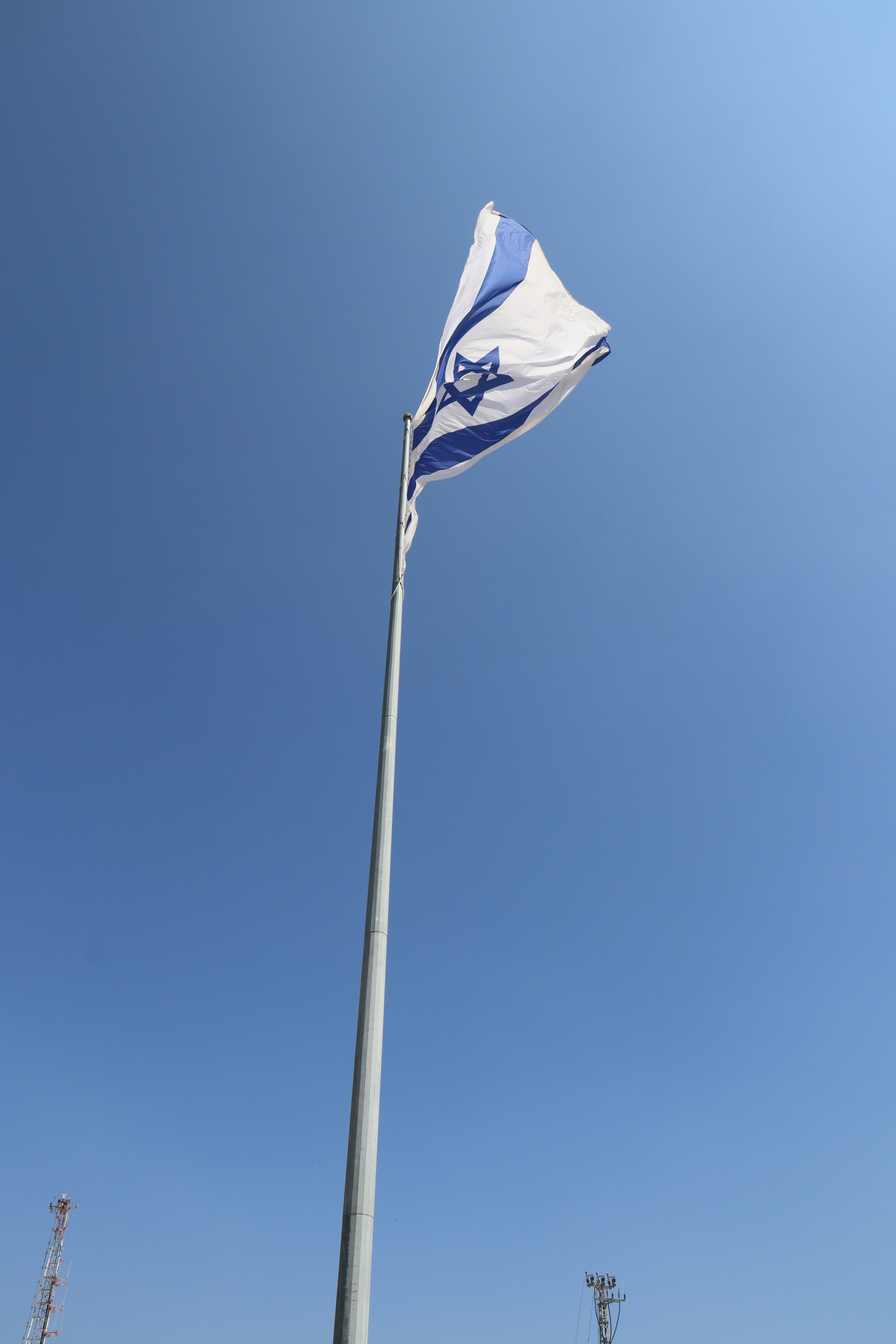 A bandeira de Israel tremulando contra um céu azul claro.