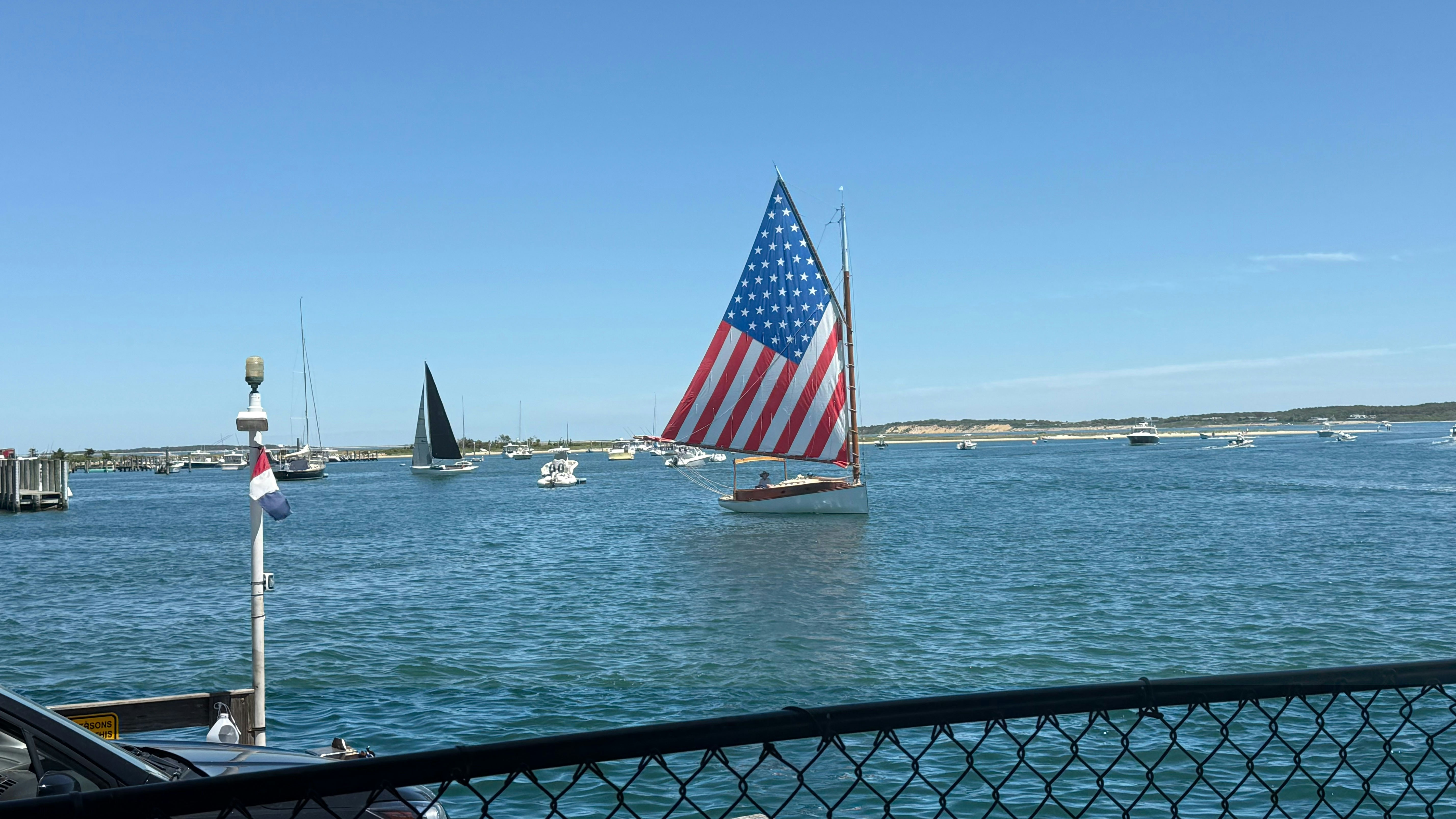 A sailboat with an american flag sail on blue water.