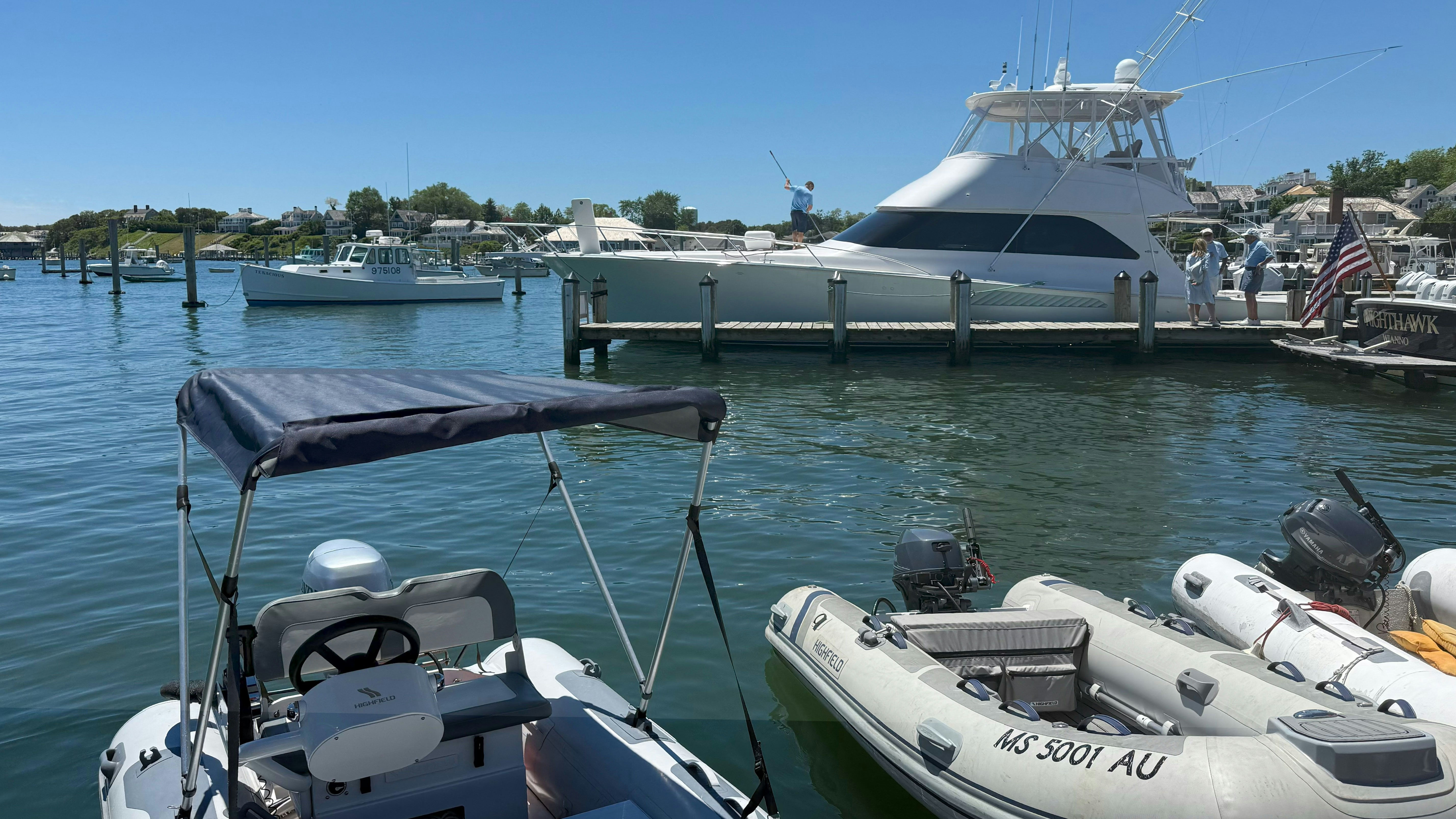 White yacht and dinghies docked in a calm marina.
