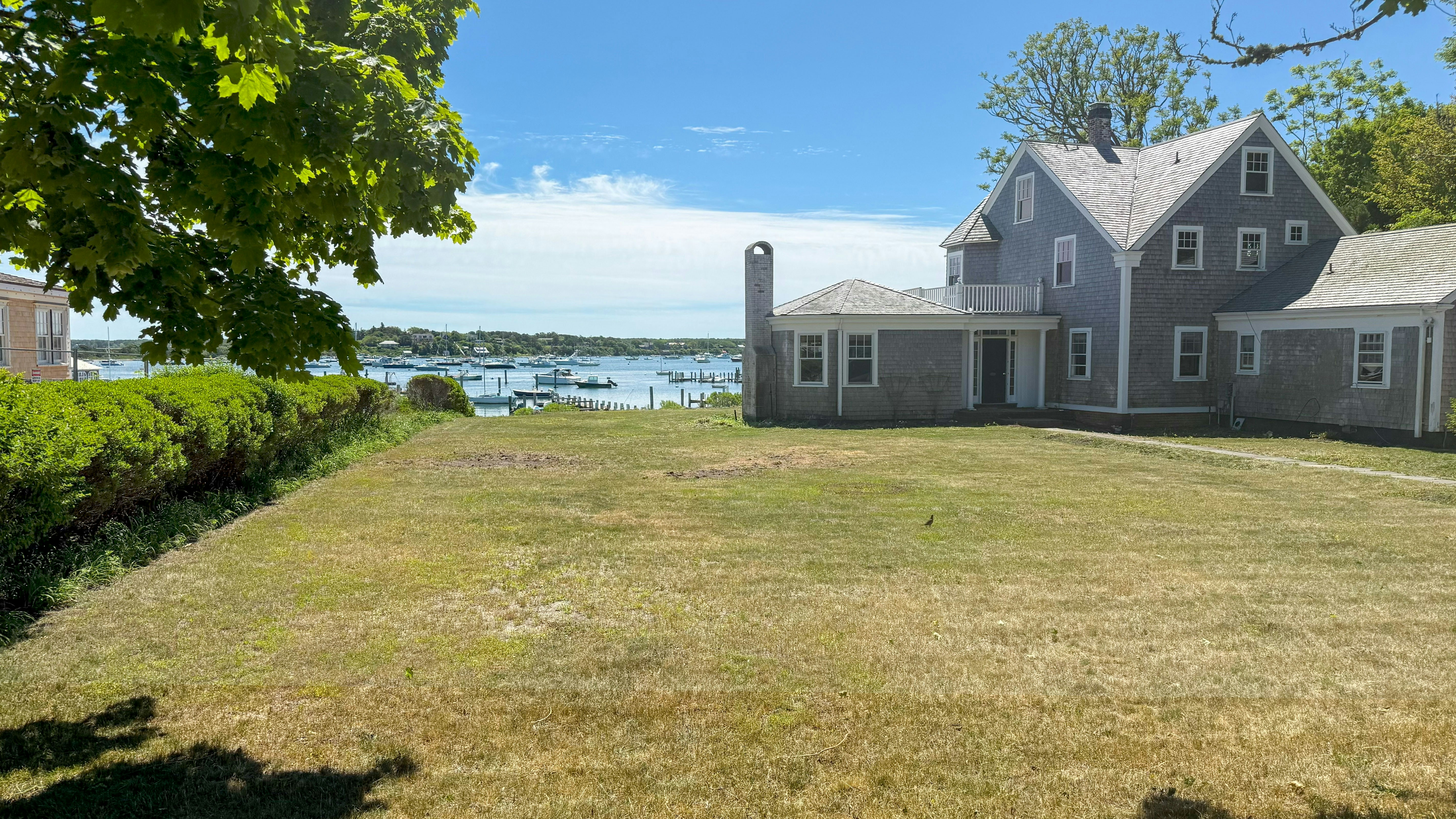 Coastal house with a lawn overlooking a bay and boats.
