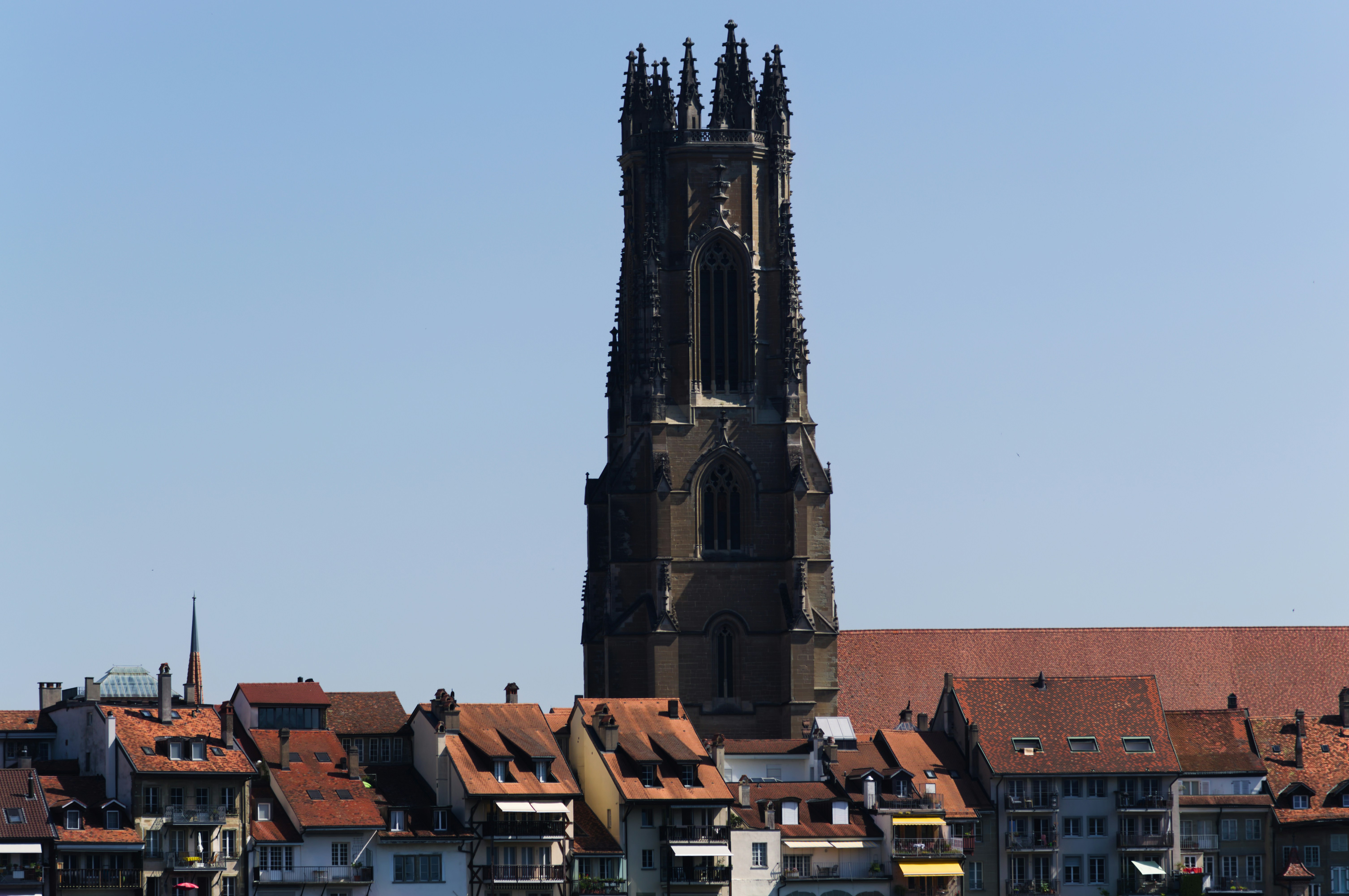 Tall gothic church tower rises above red-roofed buildings.