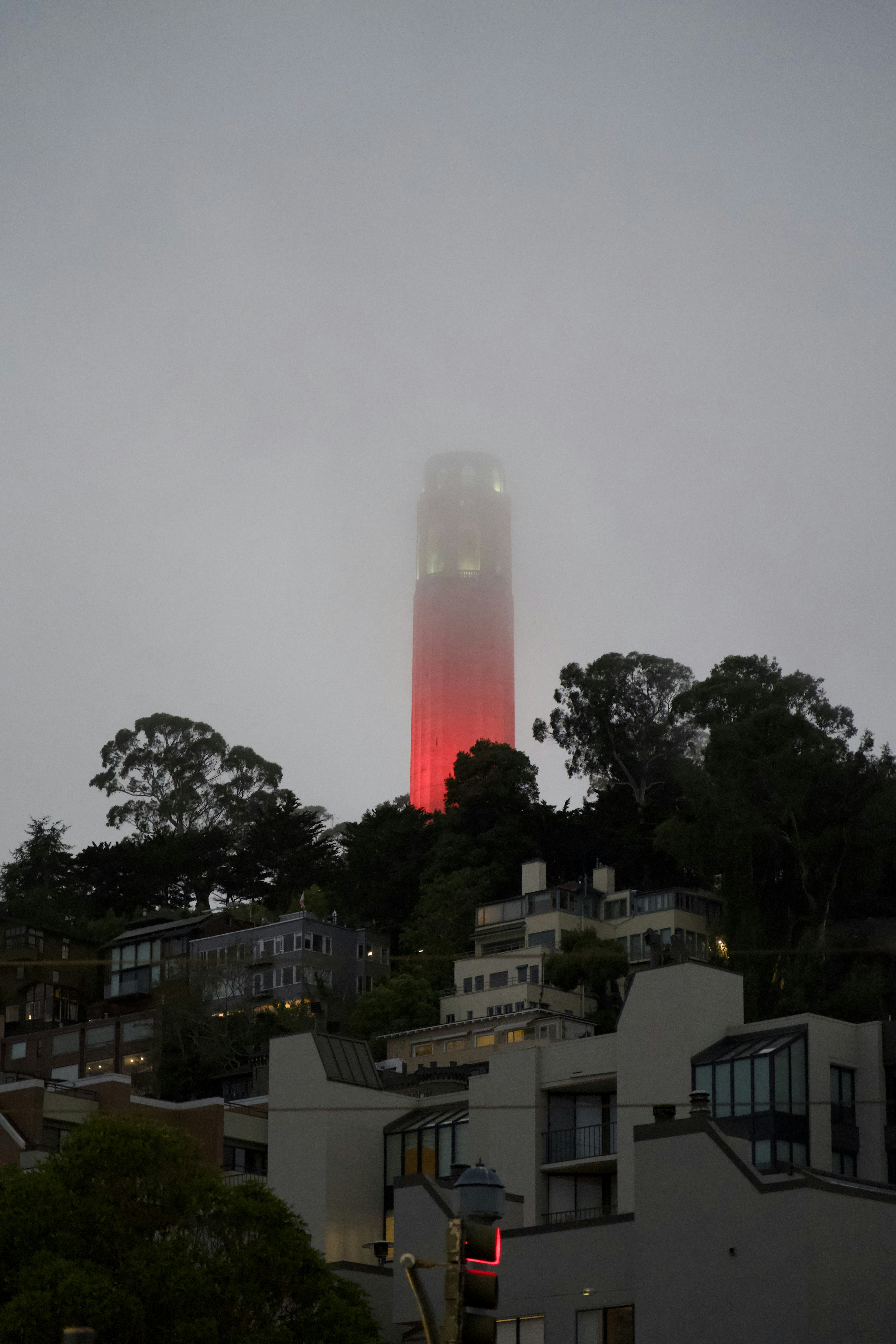 Torre rossa avvolta nella nebbia sopra le case sulle colline.