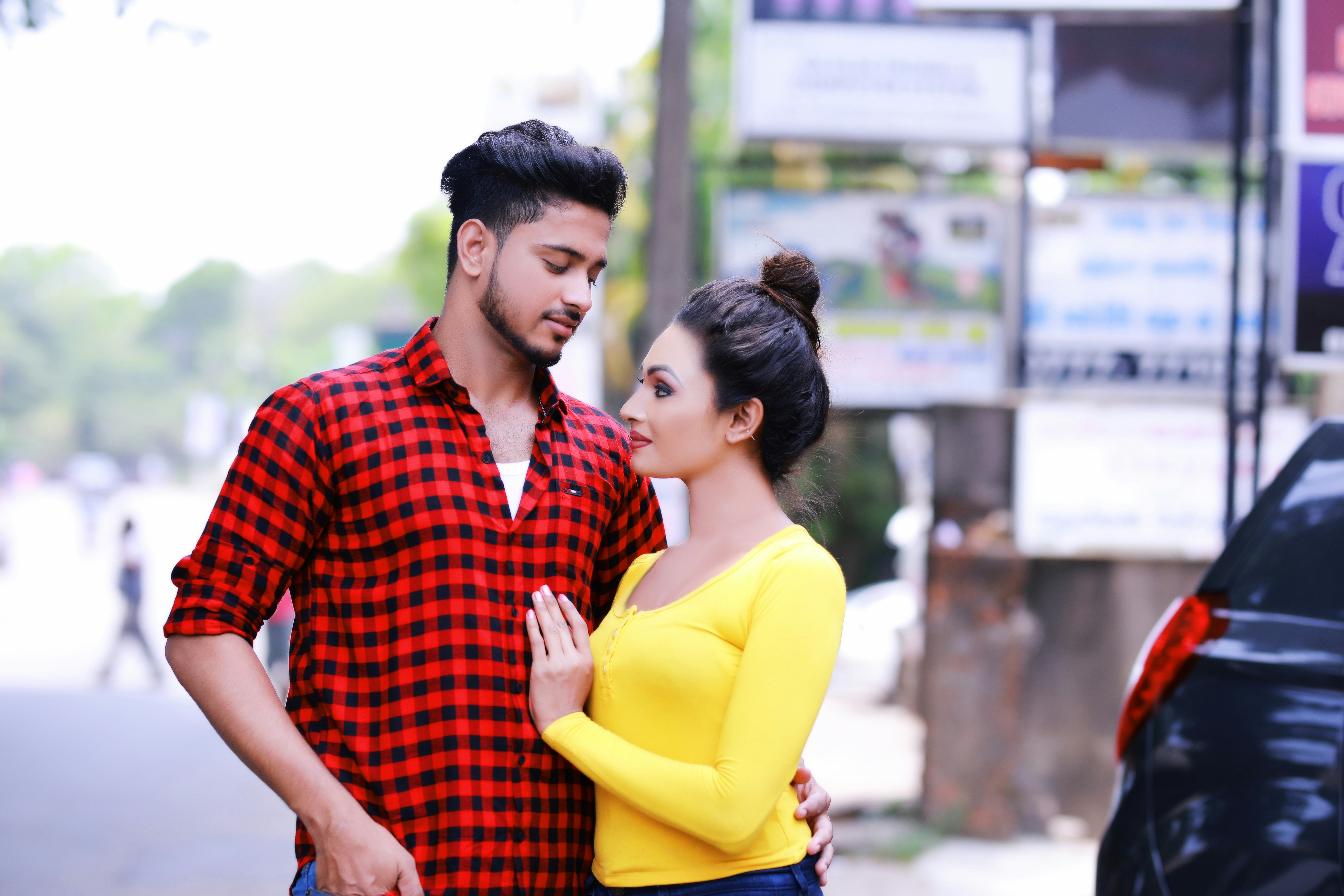 A man and woman look at each other outdoors.
