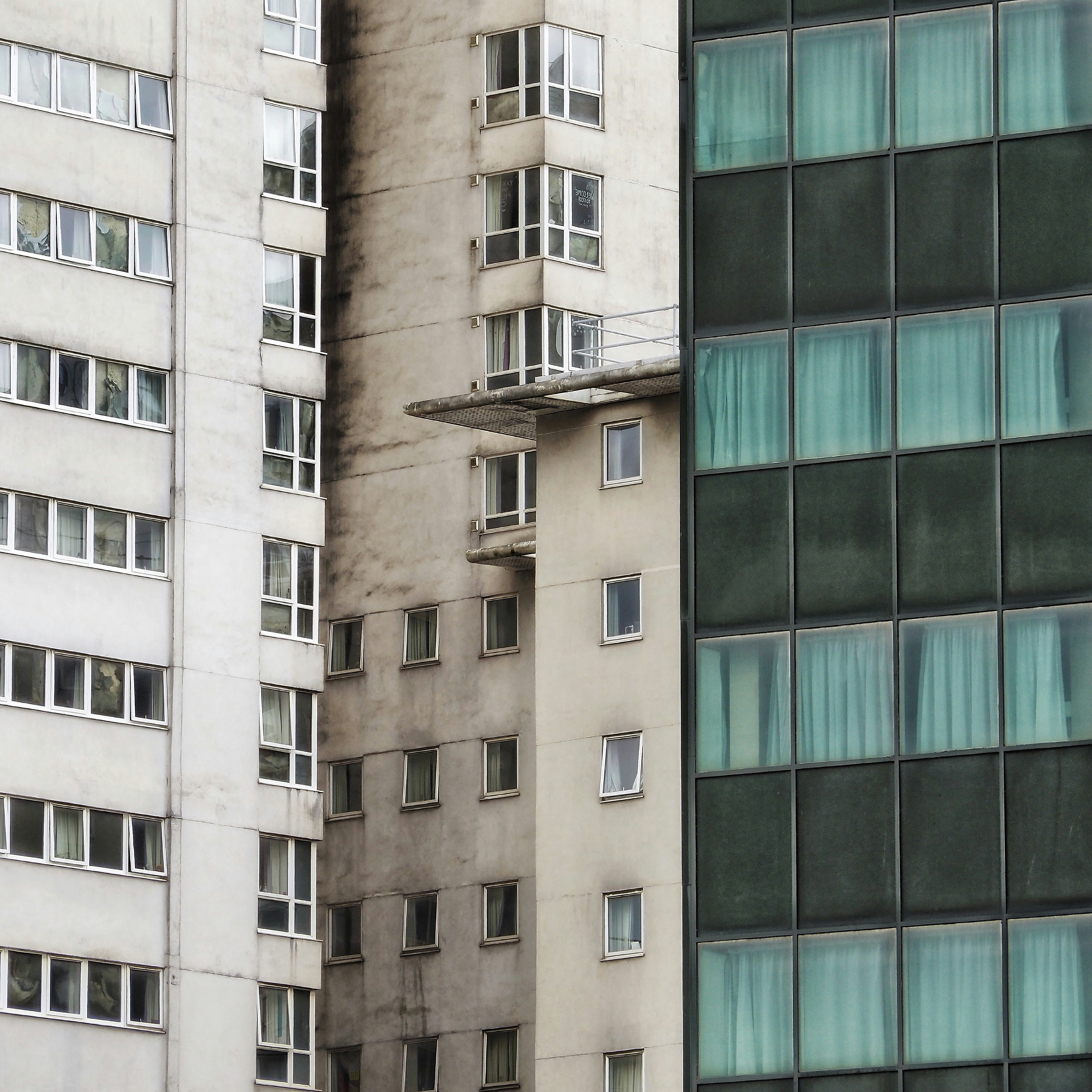 Three tall buildings with numerous windows in an urban setting.
