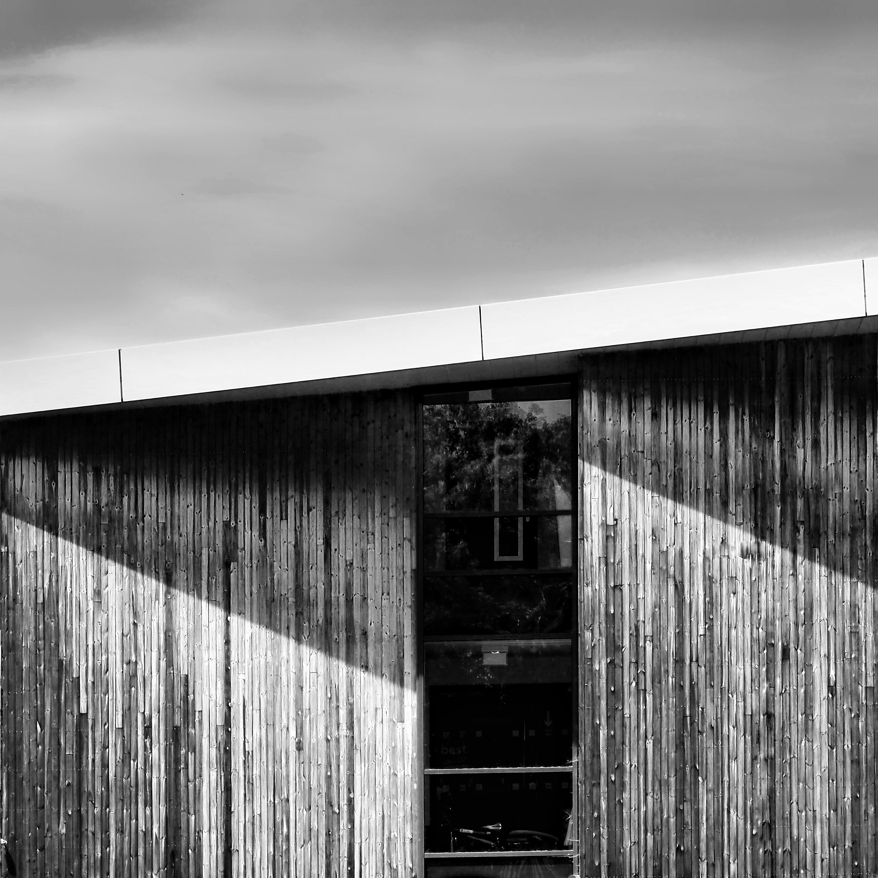 Black and white modern building with wooden facade and window.