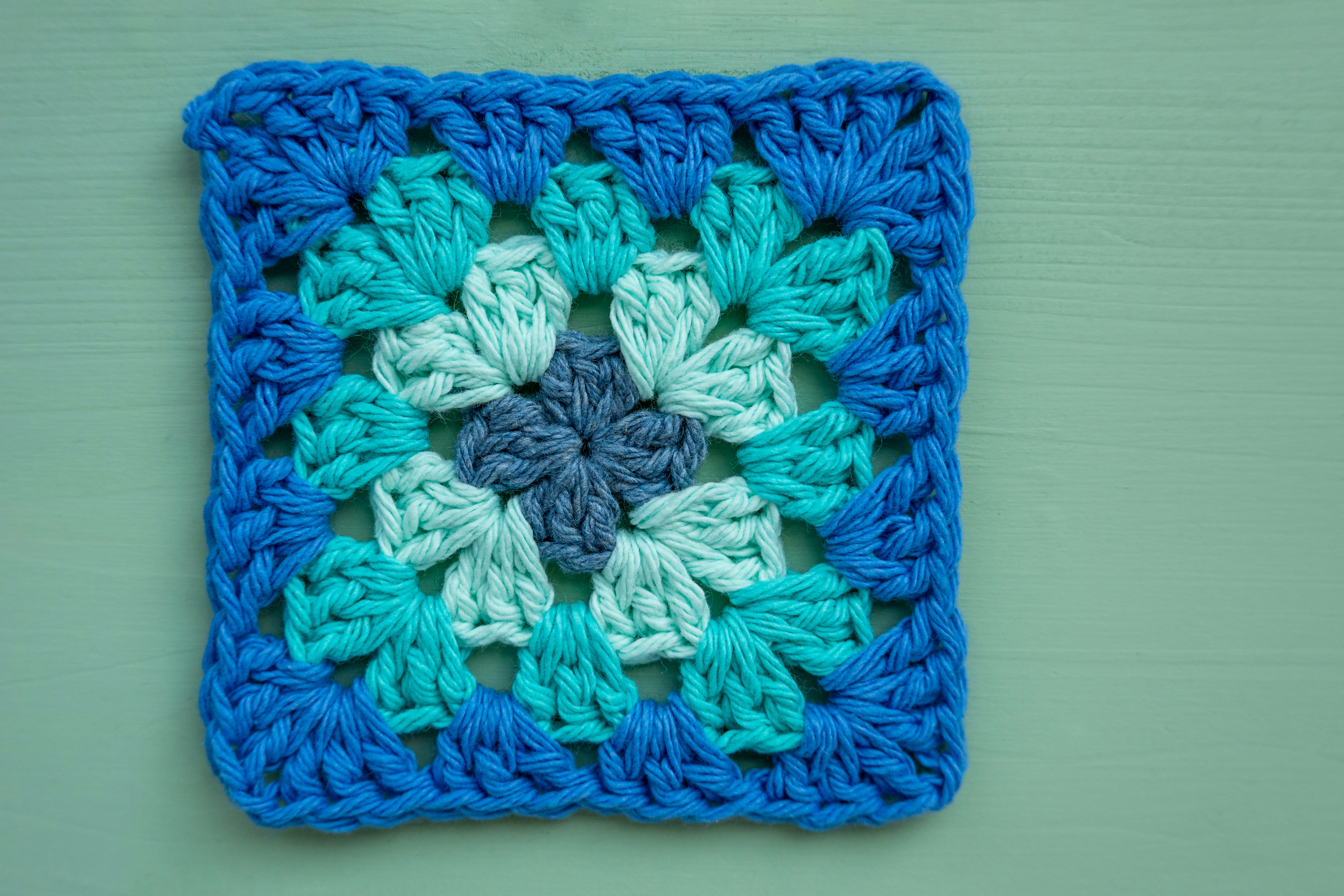 A blue and teal crocheted granny square.