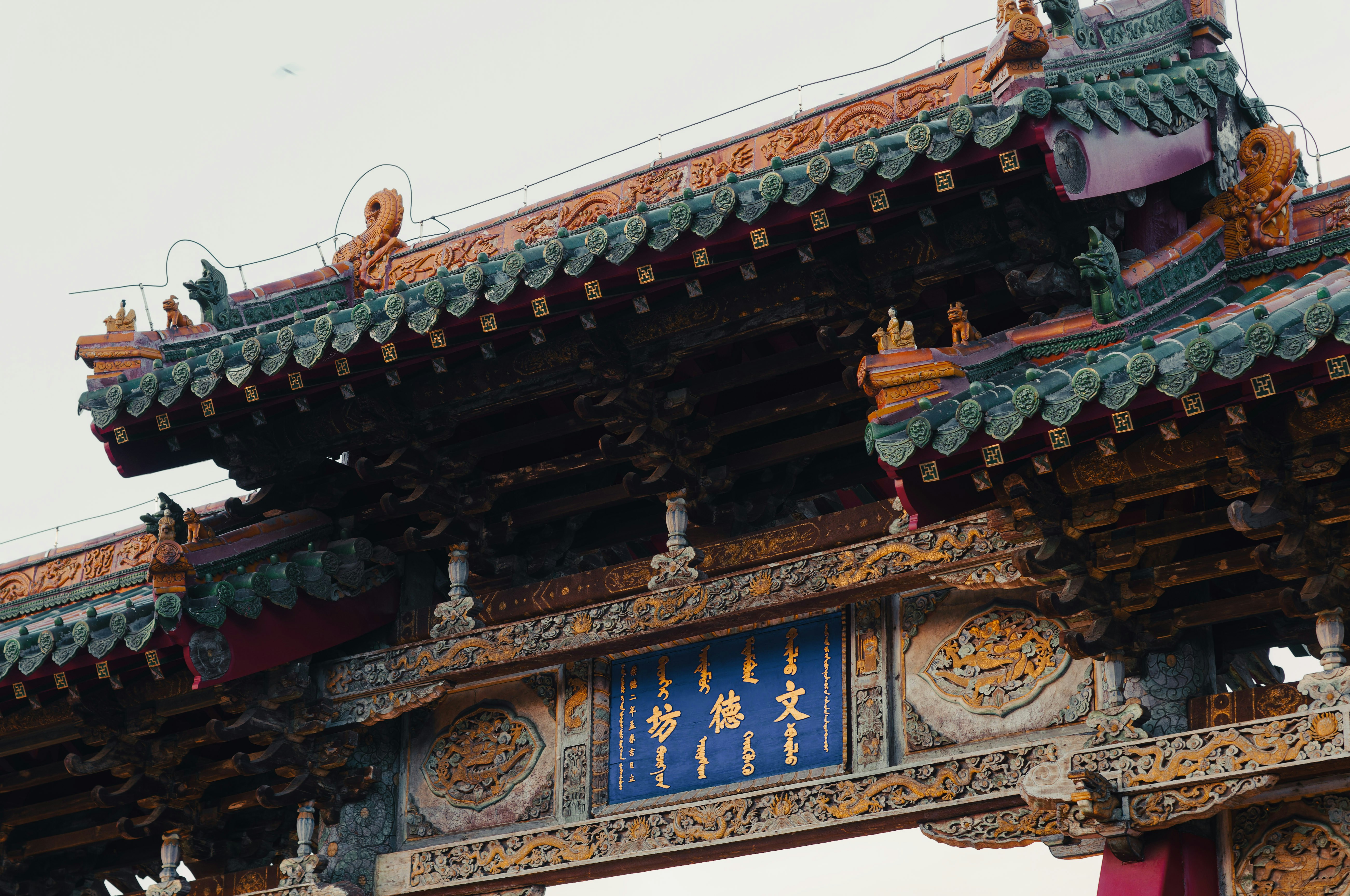 Ornate traditional archway with blue sign and green roof.